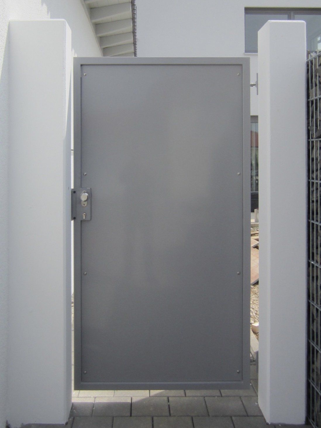 Ein graues Metalltor befindet sich zwischen zwei weißen Säulen