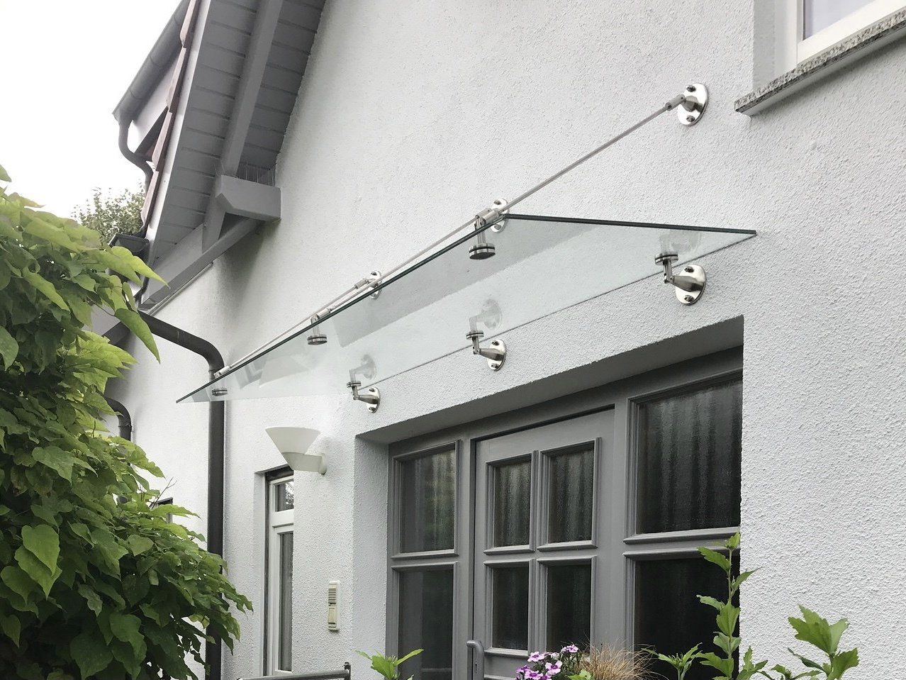 Ein weißes Haus mit einem Glasdach über der Tür