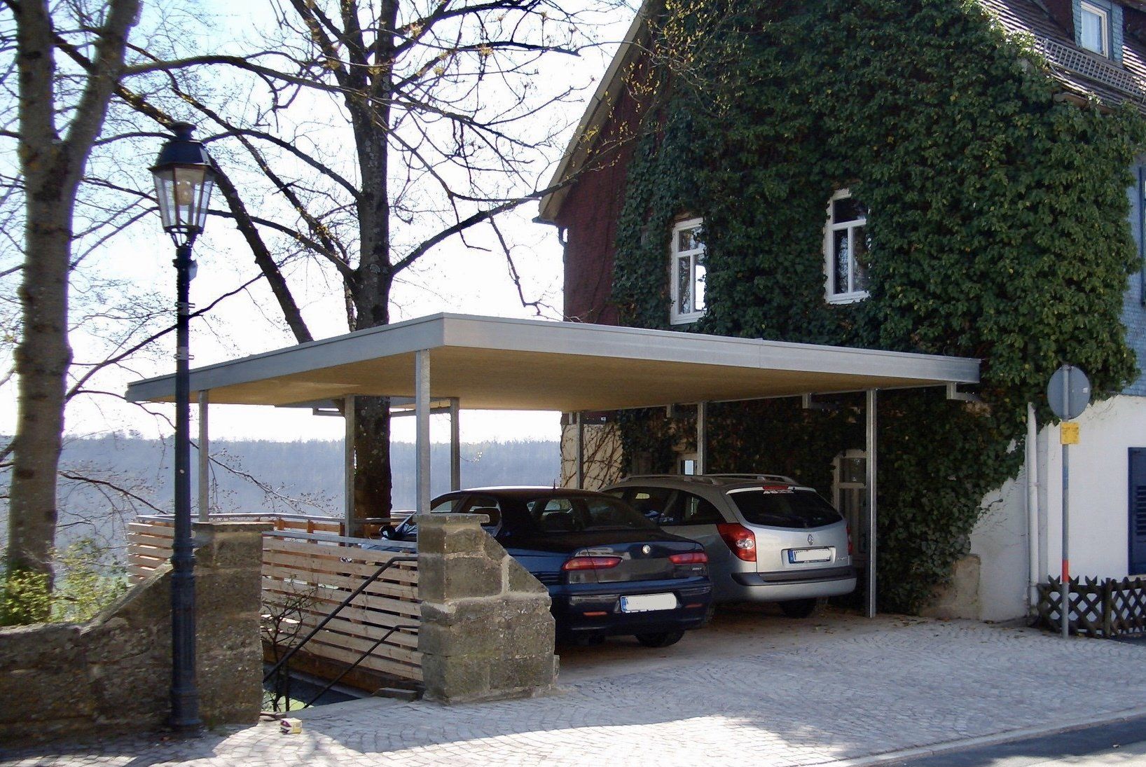 Zwei Autos sind unter einem Carport vor einem Haus geparkt
