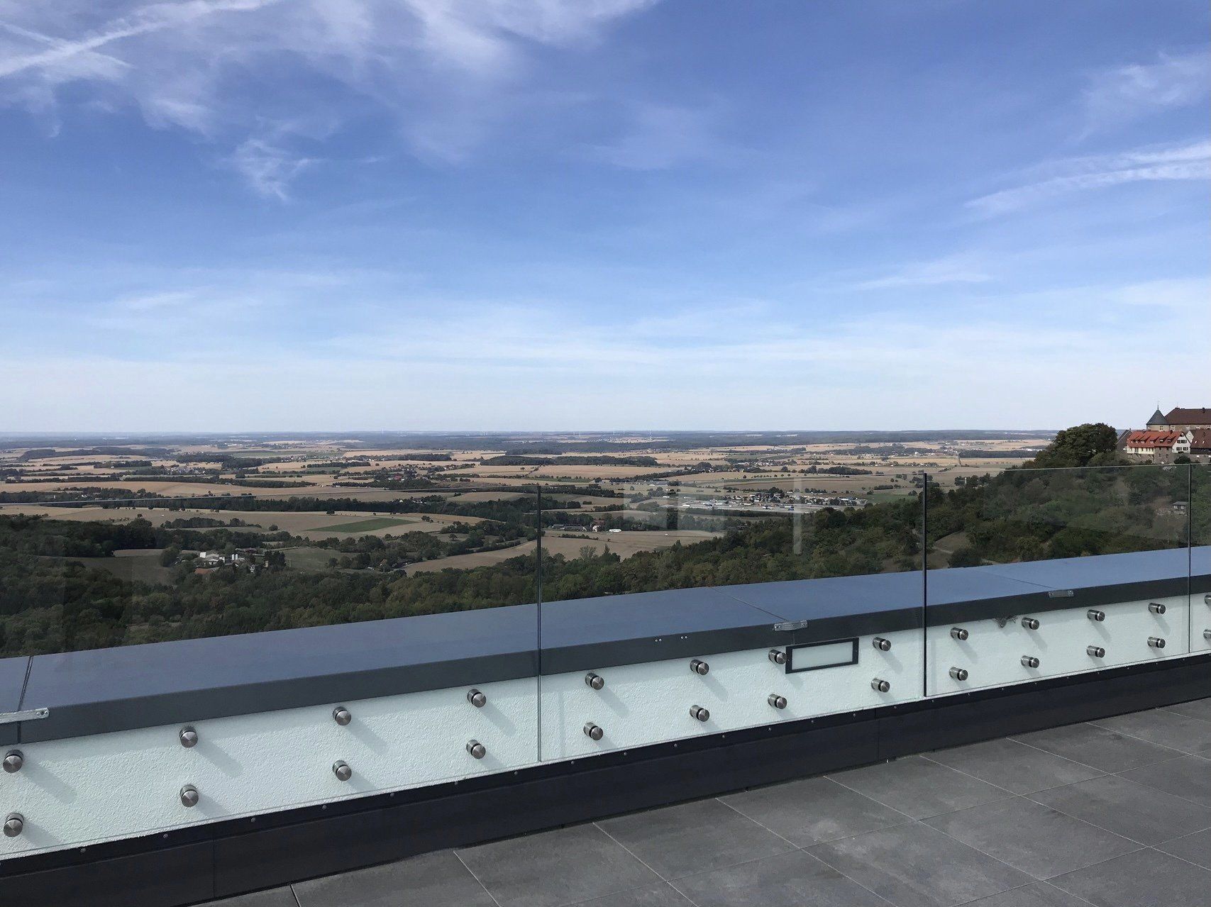Ein Blick auf eine Landschaft von einem Balkon mit Glasgeländer.