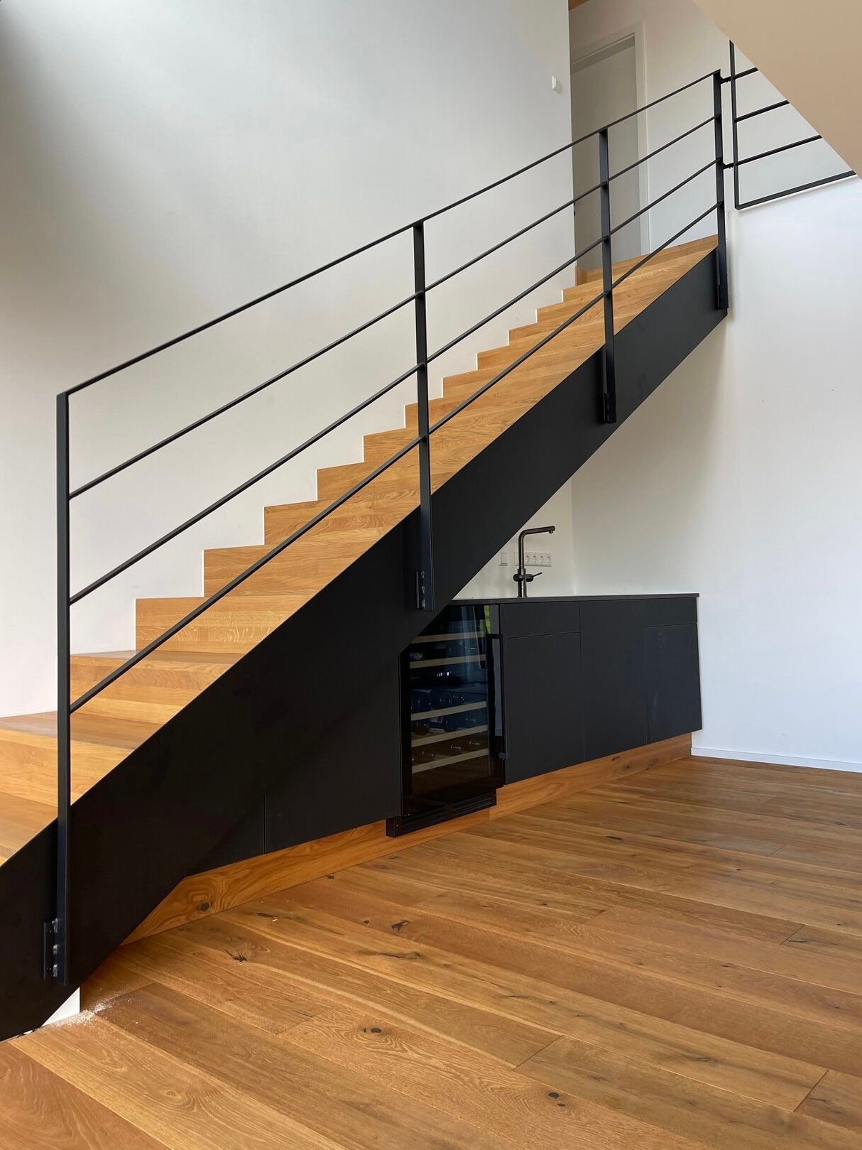 Eine Treppe mit schwarzem Geländer und Holzstufen