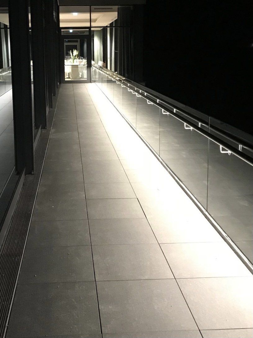 Ein langer Flur mit einem Glasgeländer ist nachts beleuchtet.