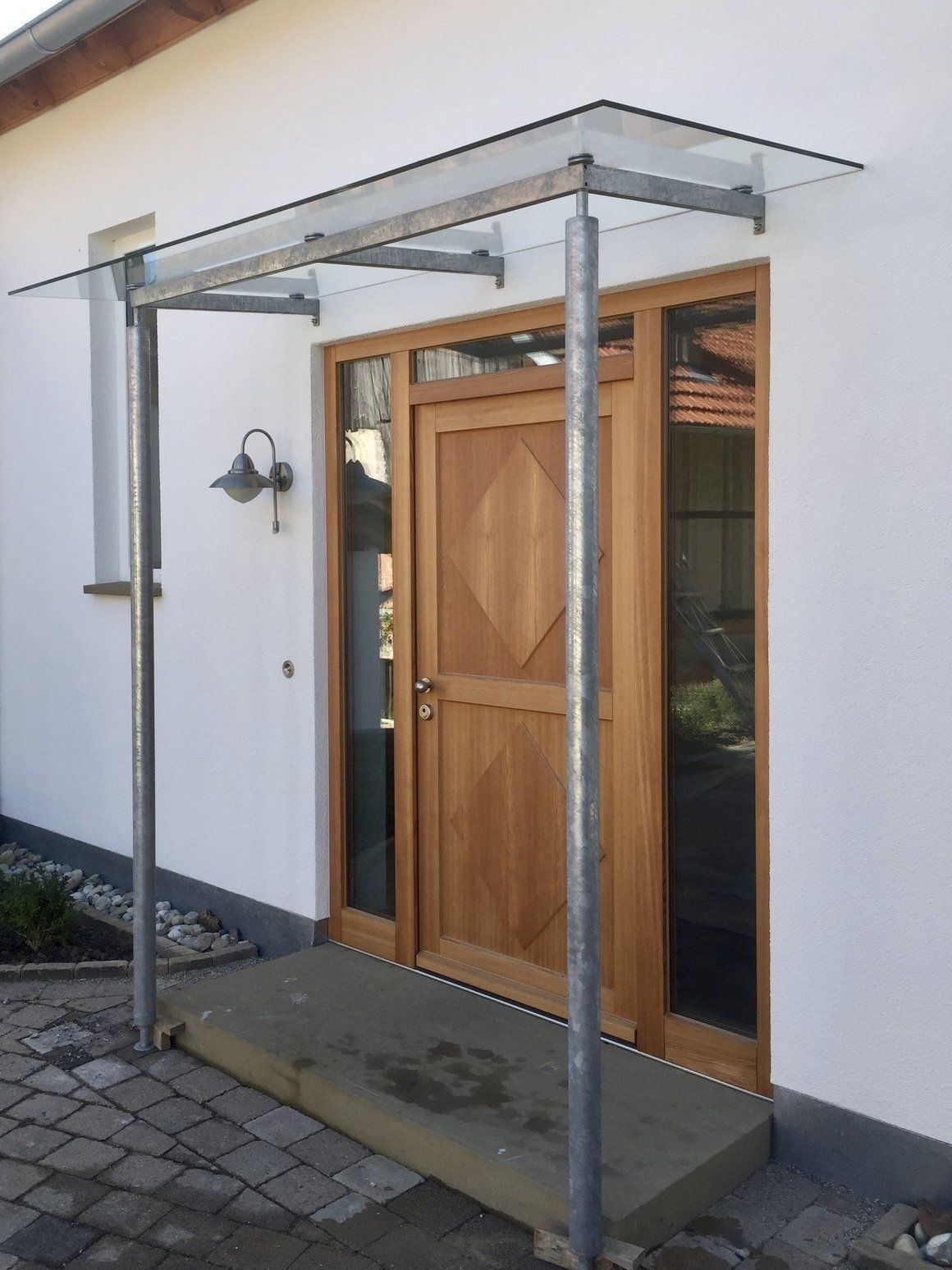 Ein weißes Gebäude mit einer Holztür und einem Glasdach darüber