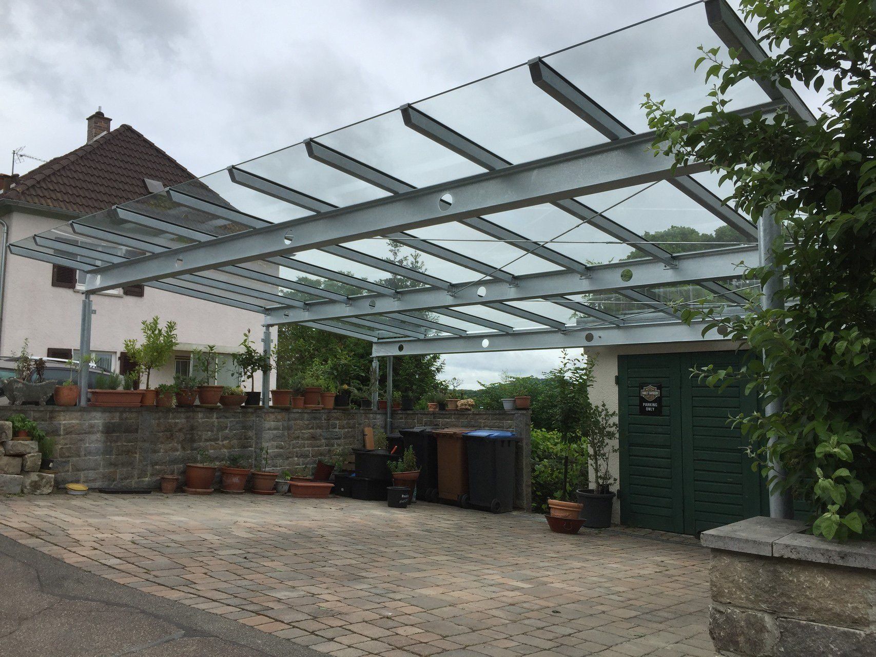 Ein Carport mit Glasdach vor einem Haus