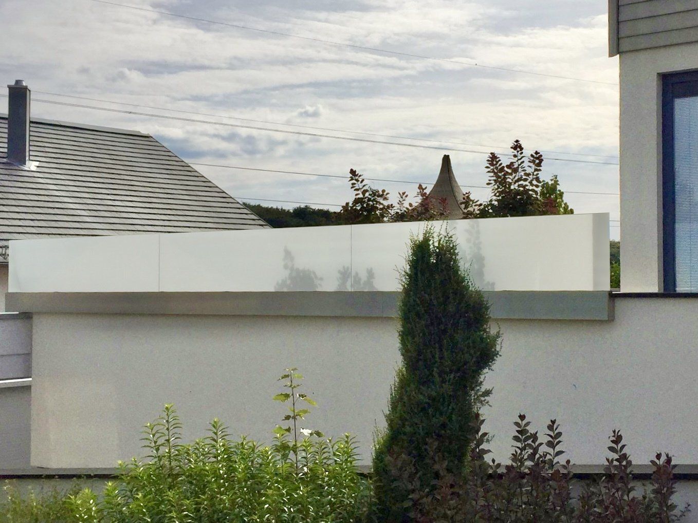 Ein weißes Gebäude mit einem Balkon und Bäumen davor