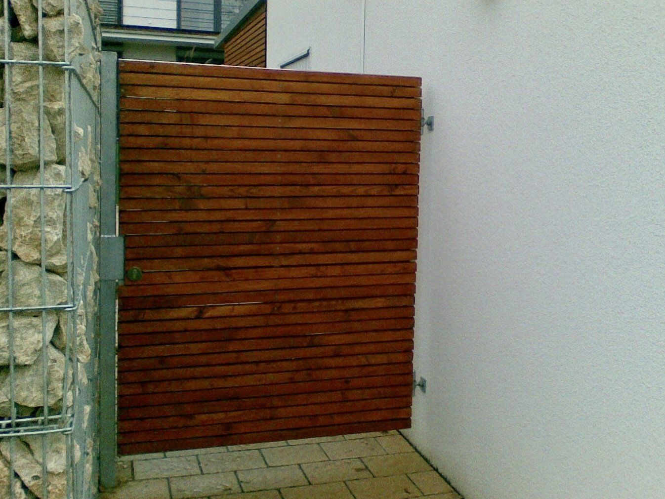 Ein Holzzaun steht neben einer weißen Wand