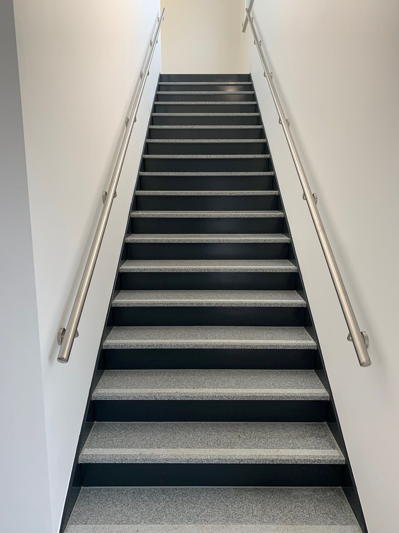 Eine Treppe, die zu einer weißen Wand hinaufführt.