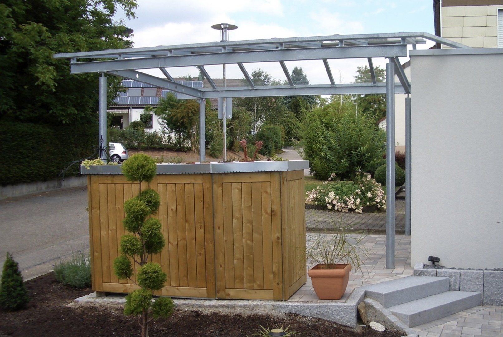 Eine Holzkiste mit einem Metalldach steht vor einem Haus