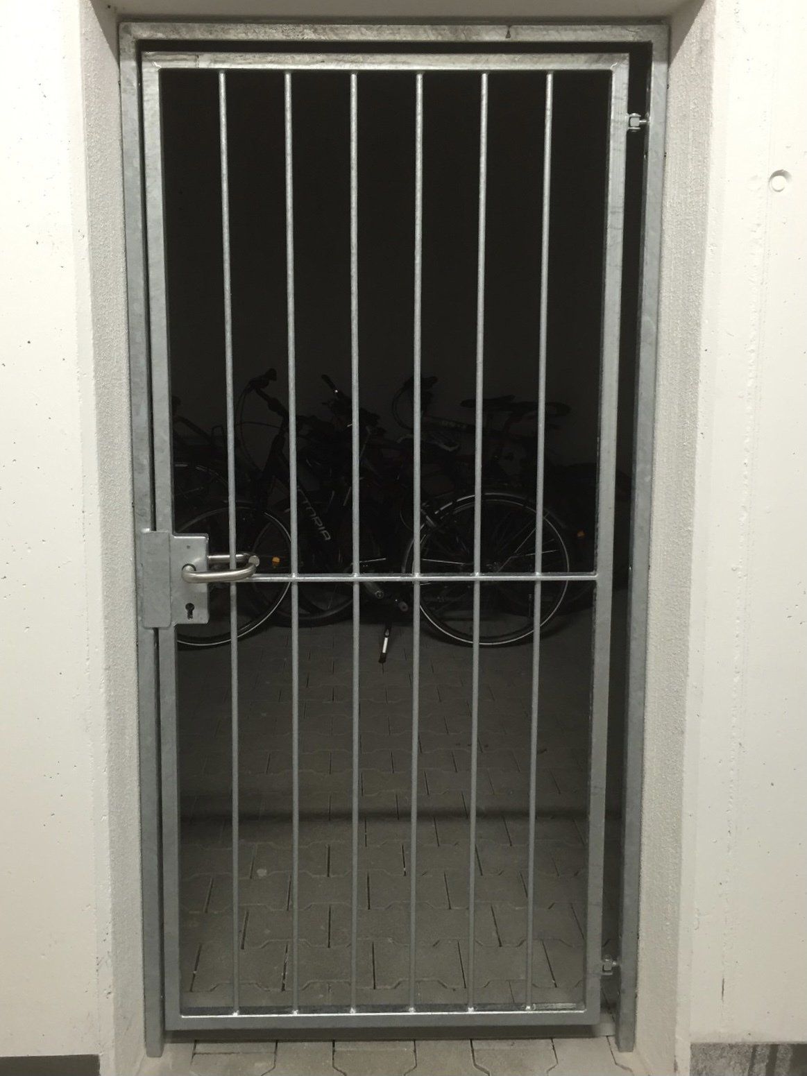 Eine vergitterte Tür führt zu einem Raum, in dem Fahrräder abgestellt sind.