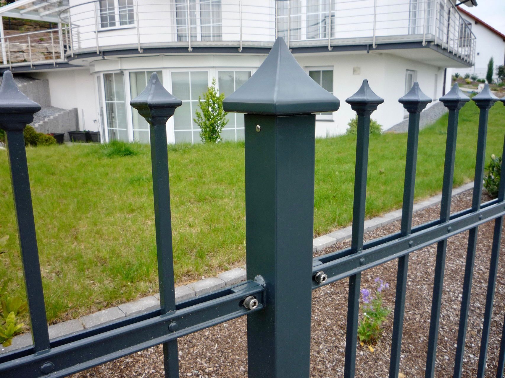 Ein schmiedeeiserner Zaun mit einem Haus im Hintergrund