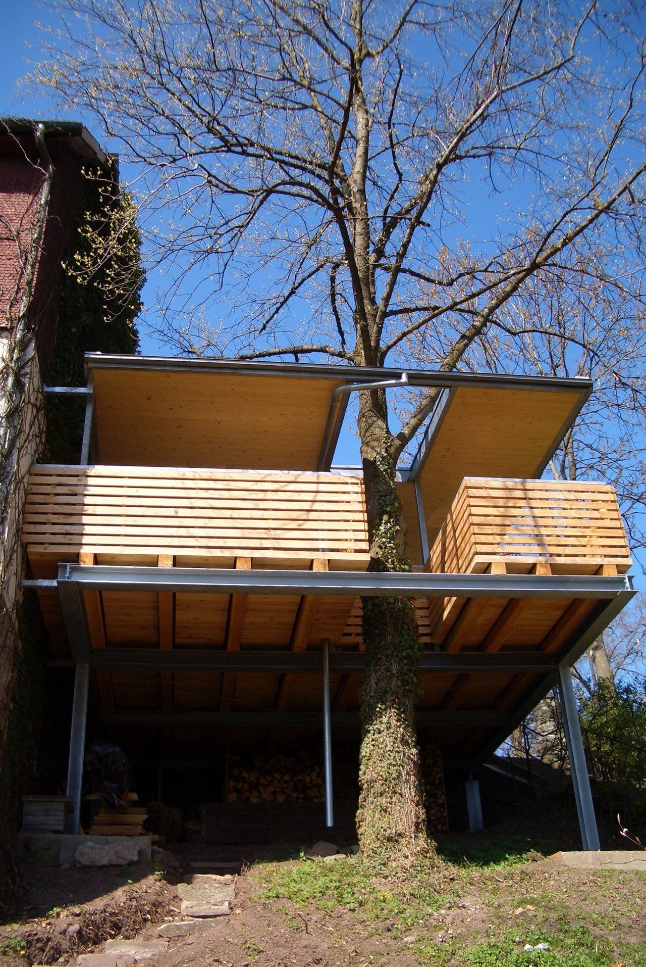 Ein Haus mit einer Holzterrasse und einem Baum im Hintergrund.