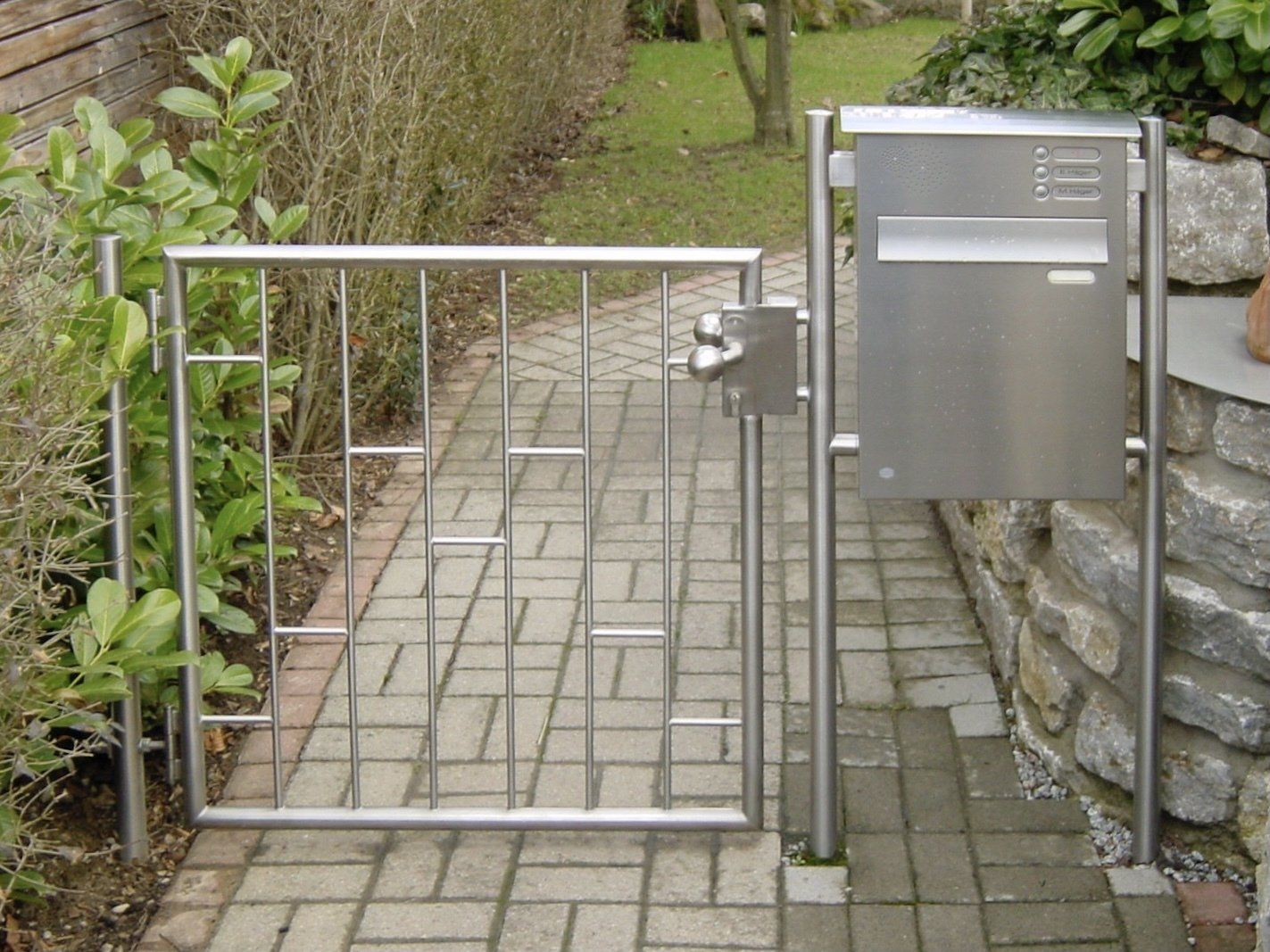 Ein Edelstahltor mit einem Briefkasten daneben