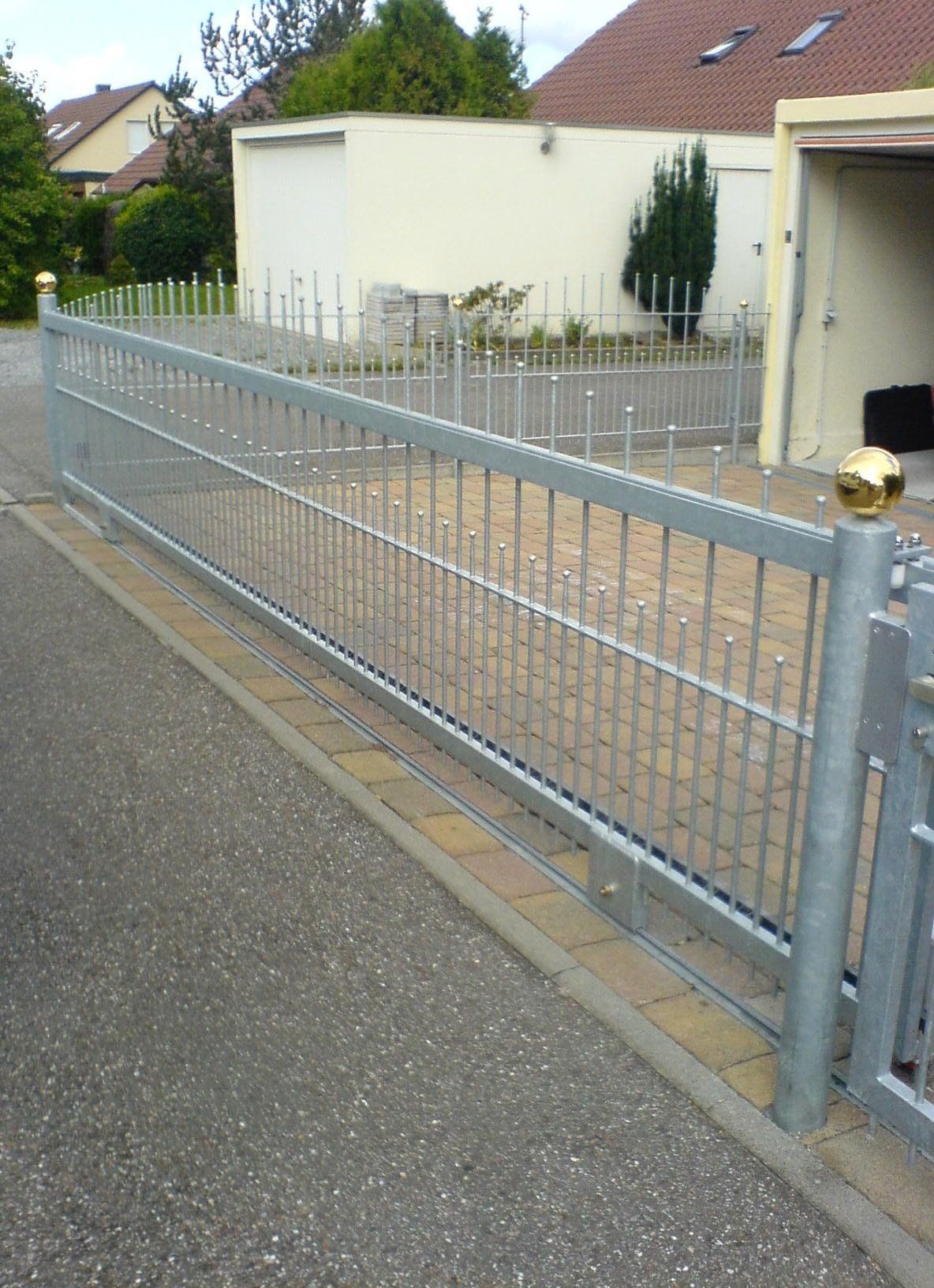 Ein Metallzaun umgibt eine Einfahrt vor einem Haus