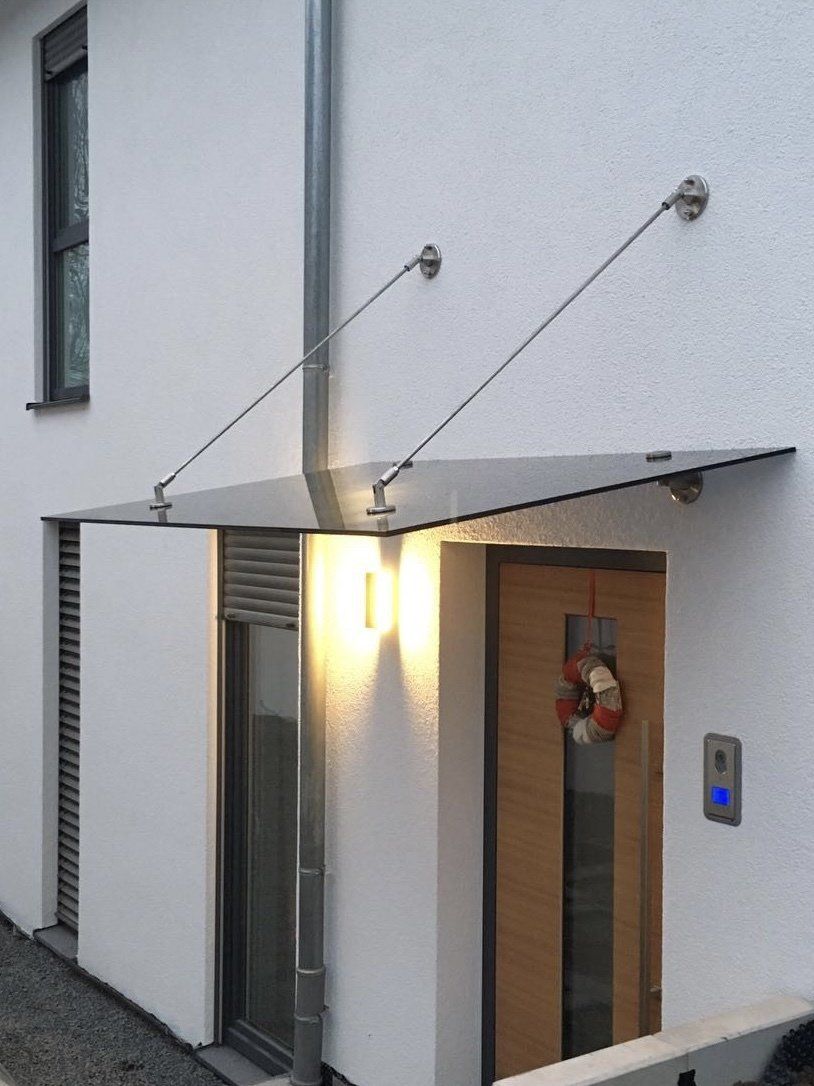 Ein weißes Haus mit einer Holztür und einem Glasdach darüber.