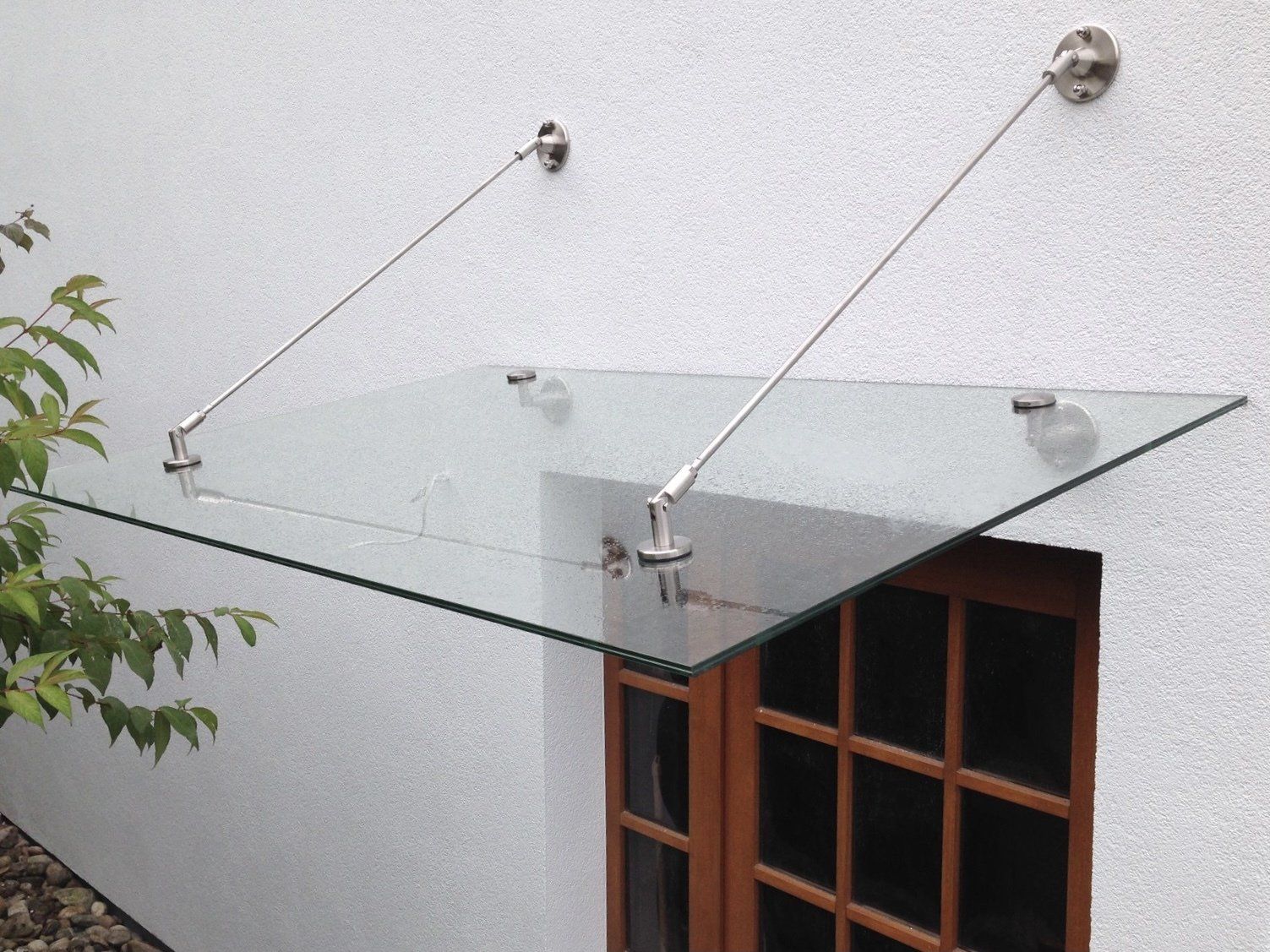 Ein Glasdach über einem Fenster an einer weißen Wand