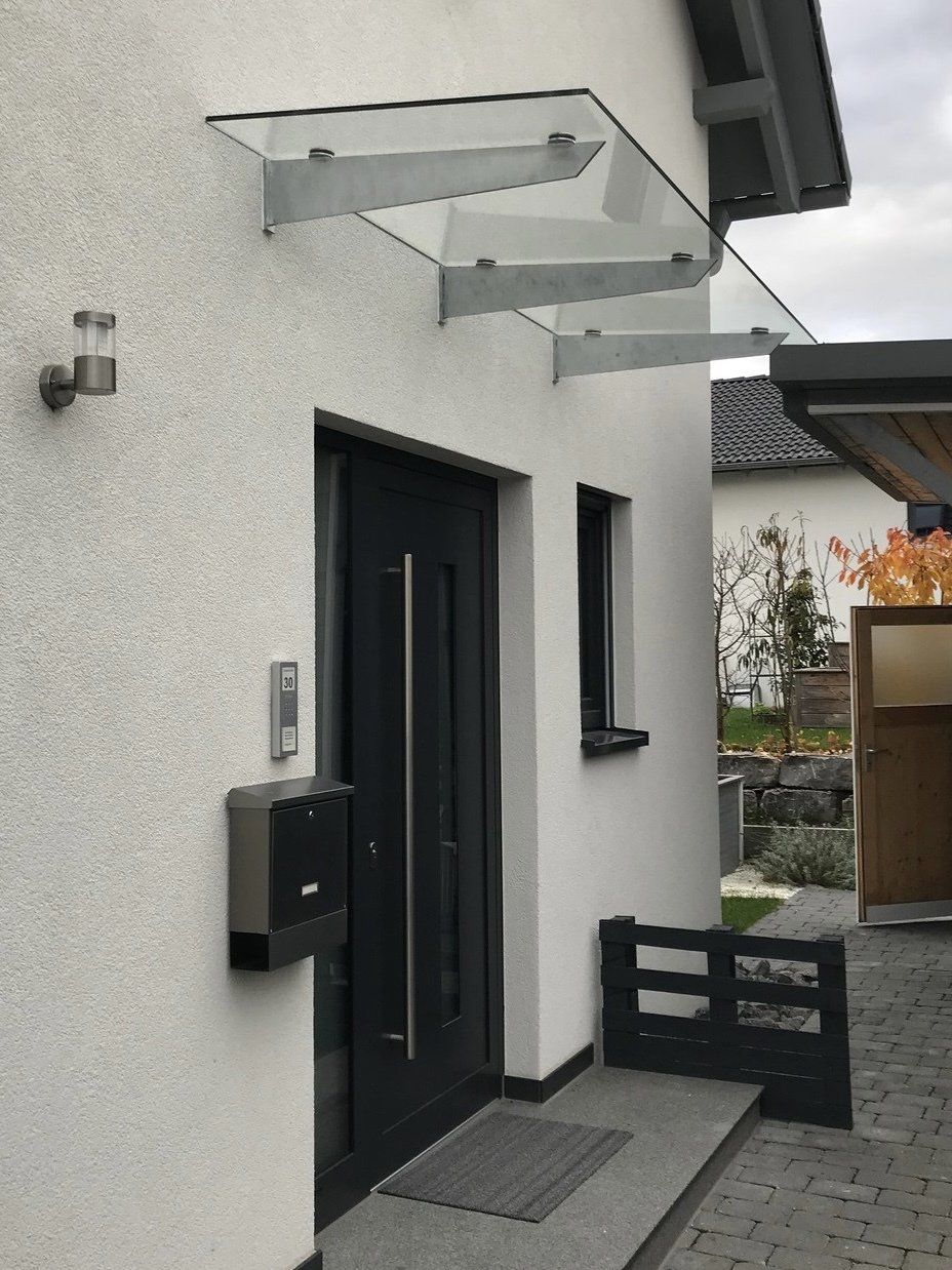 Ein weißes Haus mit einer schwarzen Tür und einem Glasdach darüber