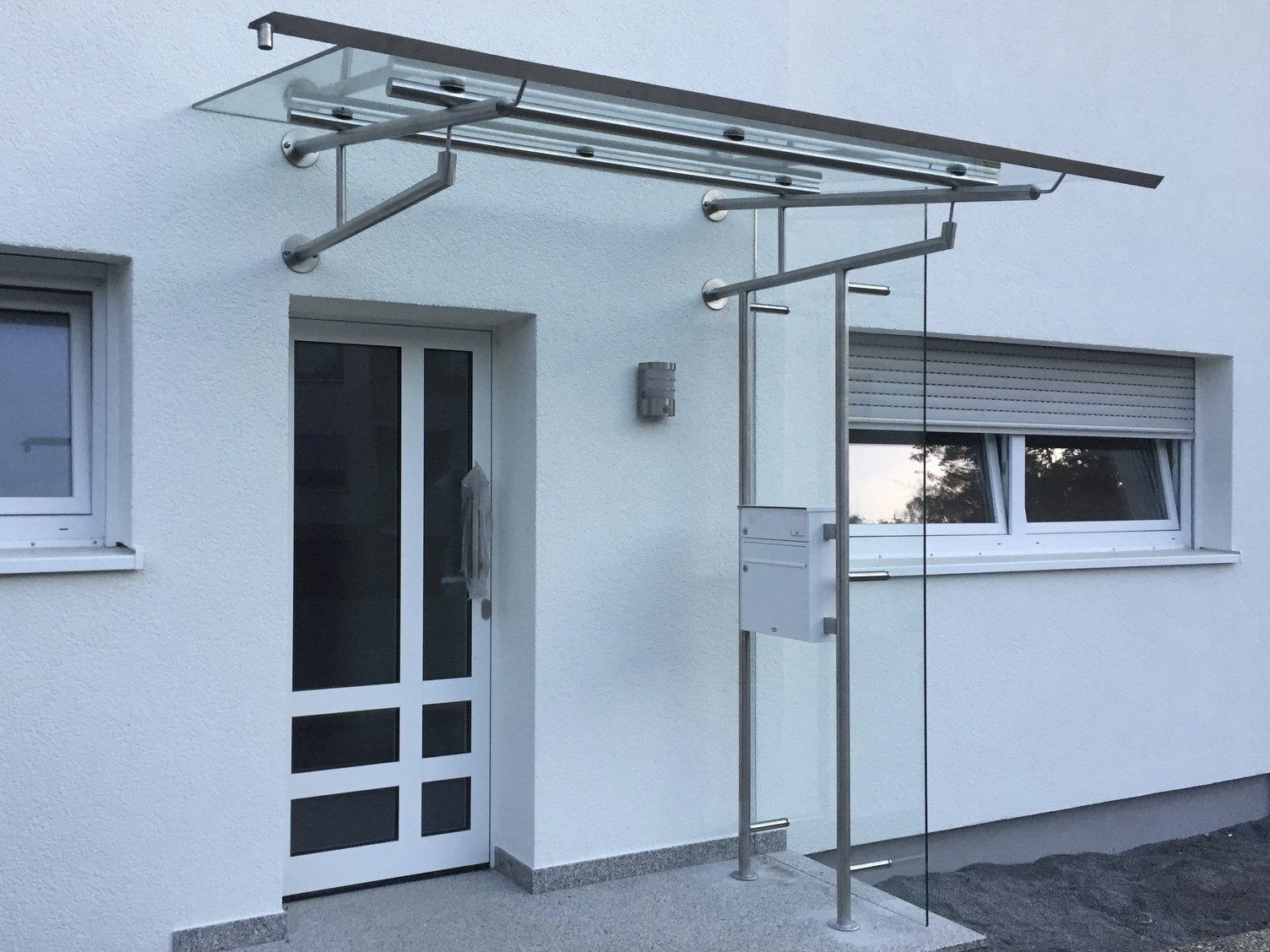 Ein weißes Gebäude mit einem Glasdach über der Tür