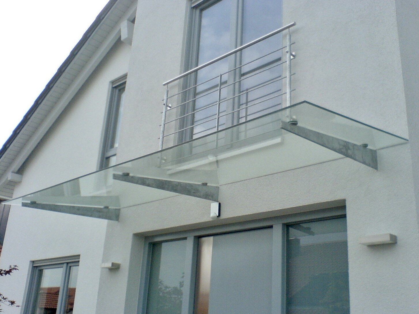 Ein weißes Haus mit einem Glasdach über der Tür