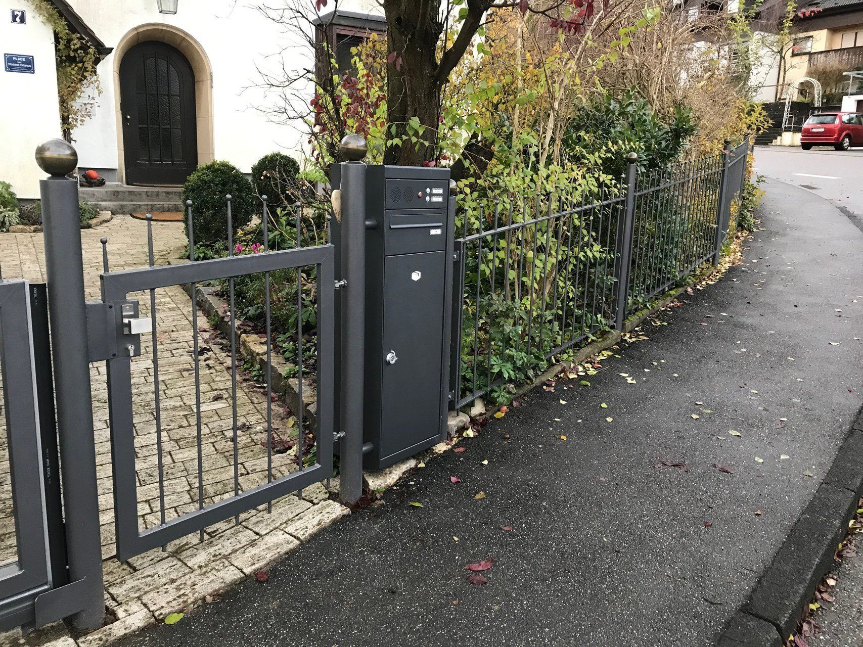 Ein Zaun mit einem Briefkasten vor einem Haus.