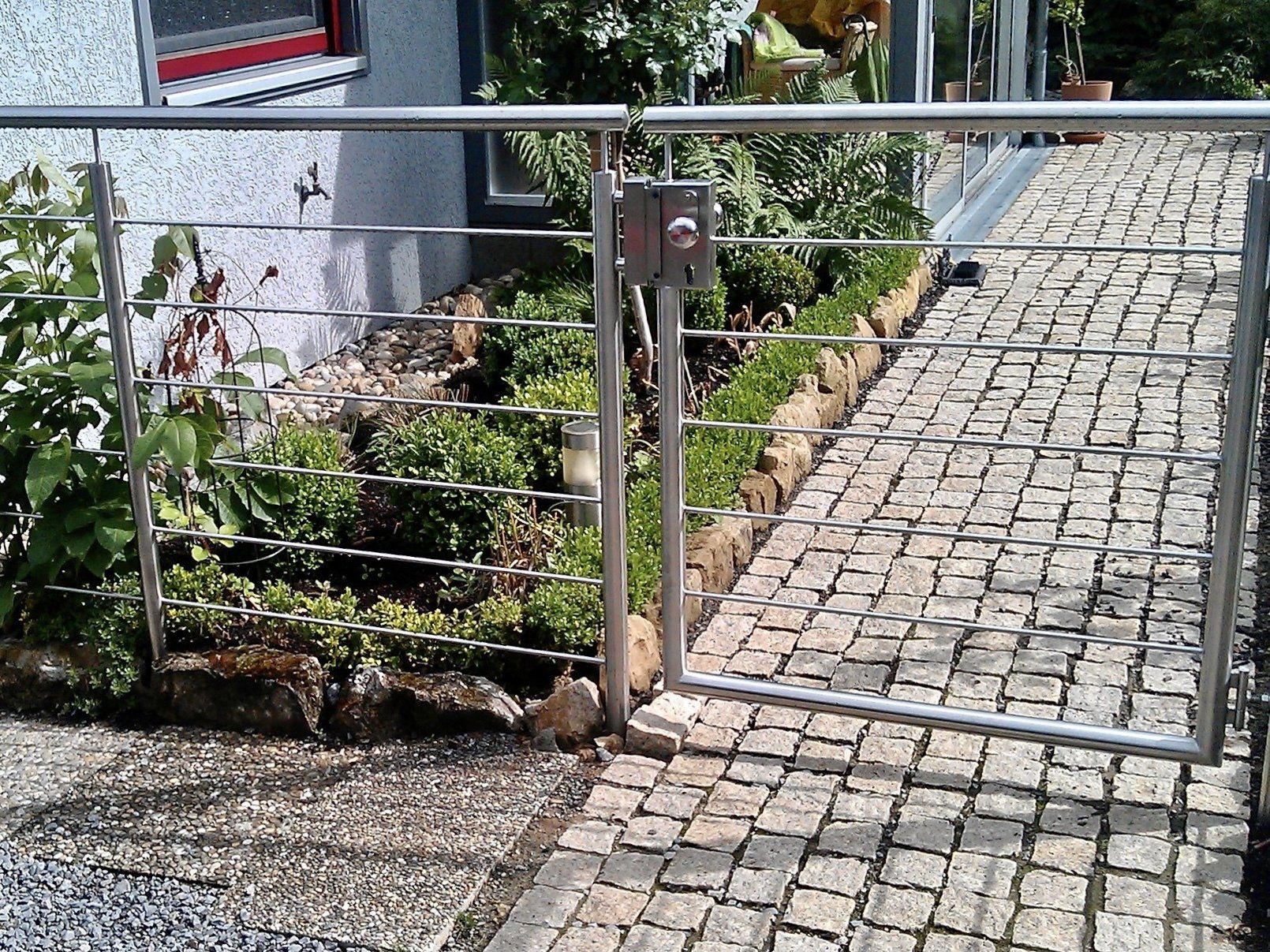 Ein Edelstahltor öffnet sich zu einer gepflasterten Auffahrt