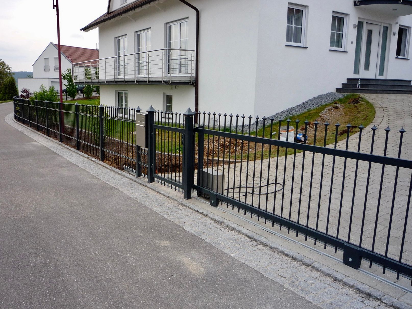 Ein weißes Haus mit einem schwarzen Zaun davor