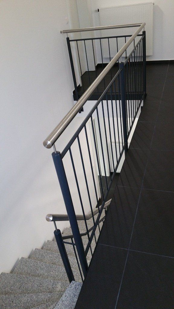 Eine Treppe mit schwarzem Geländer und weißer Wand