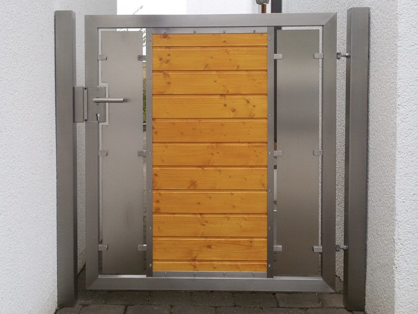 Ein Edelstahltor mit einer Holzplatte in der Mitte.