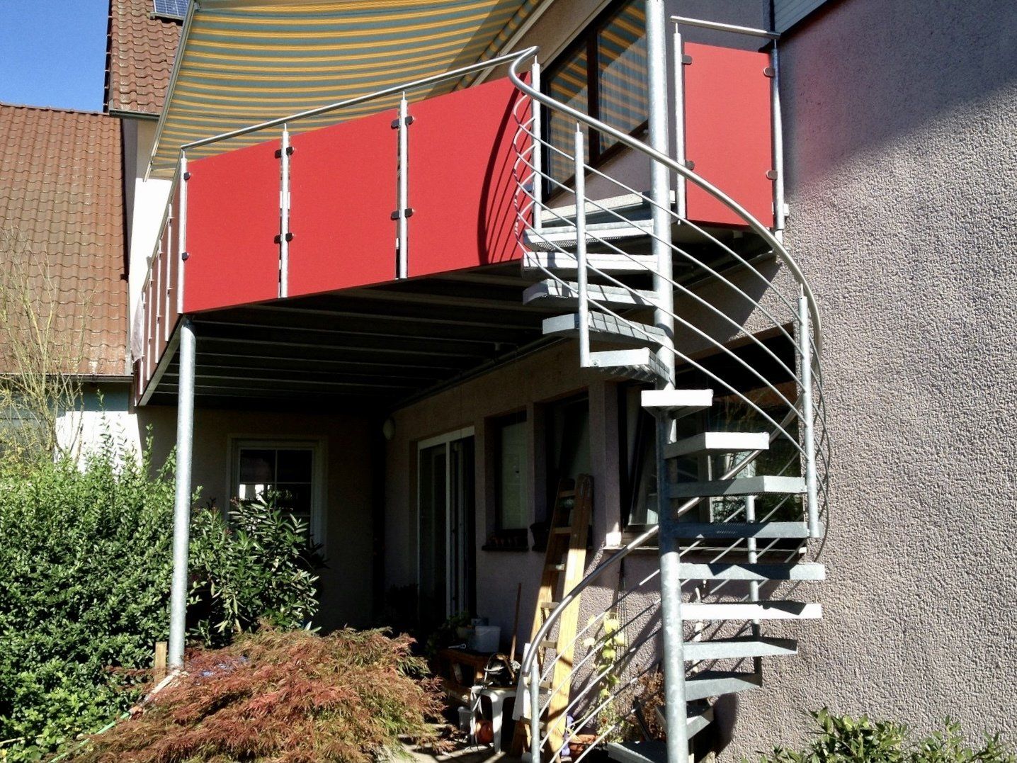 Eine Wendeltreppe, die zu einem Balkon mit einem roten Geländer führt