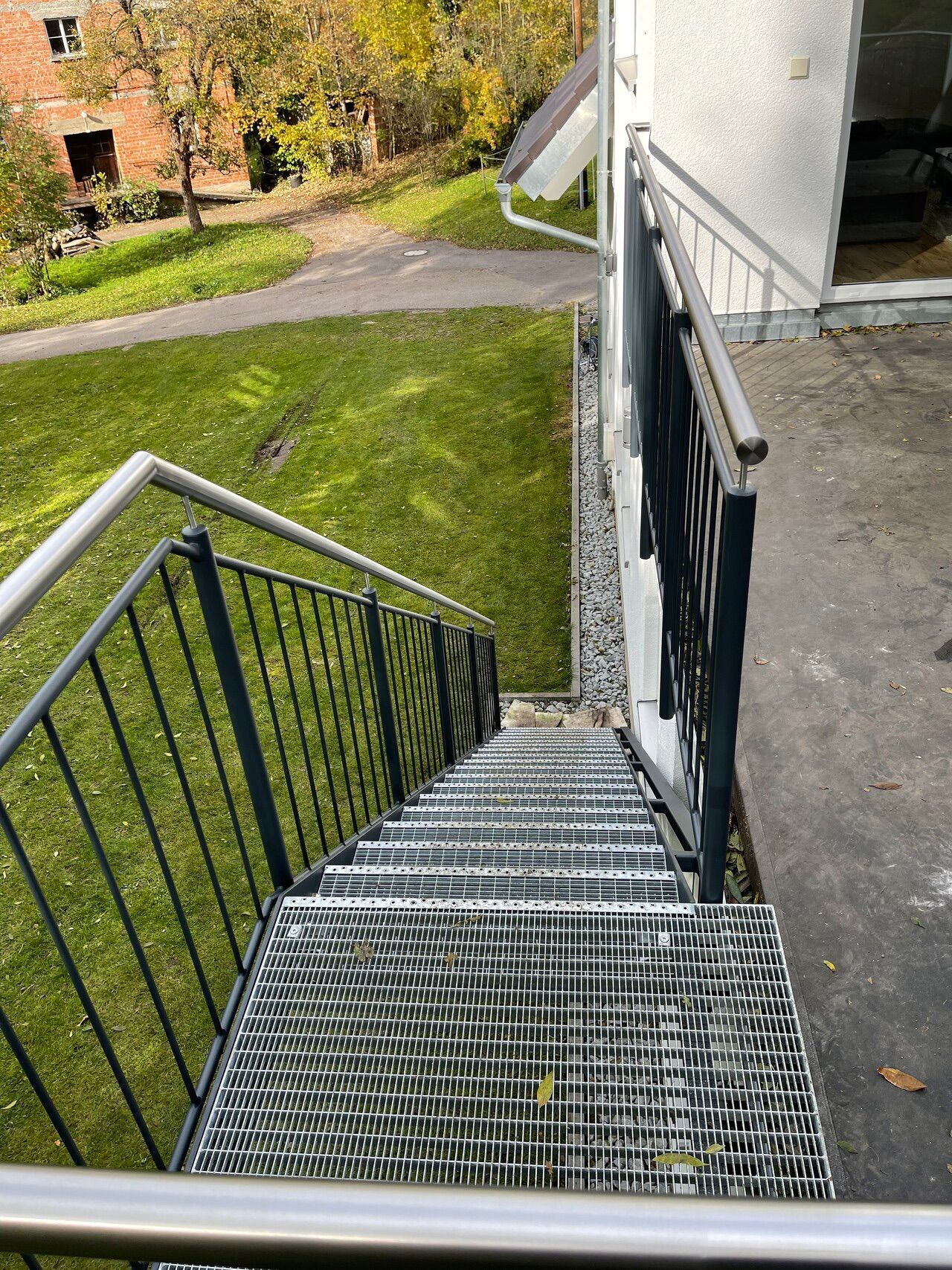 Eine Metalltreppe mit Geländer führt zu einem Haus hinauf.
