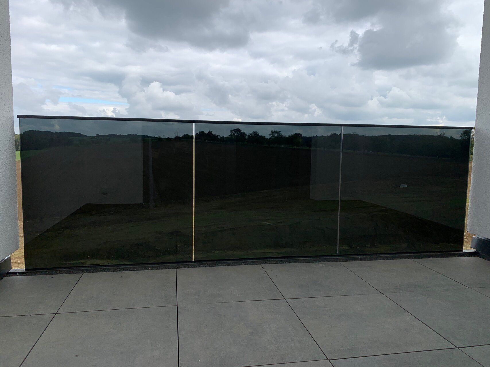 Ein Zaun mit Blick auf ein Feld und einen bewölkten Himmel dahinter.