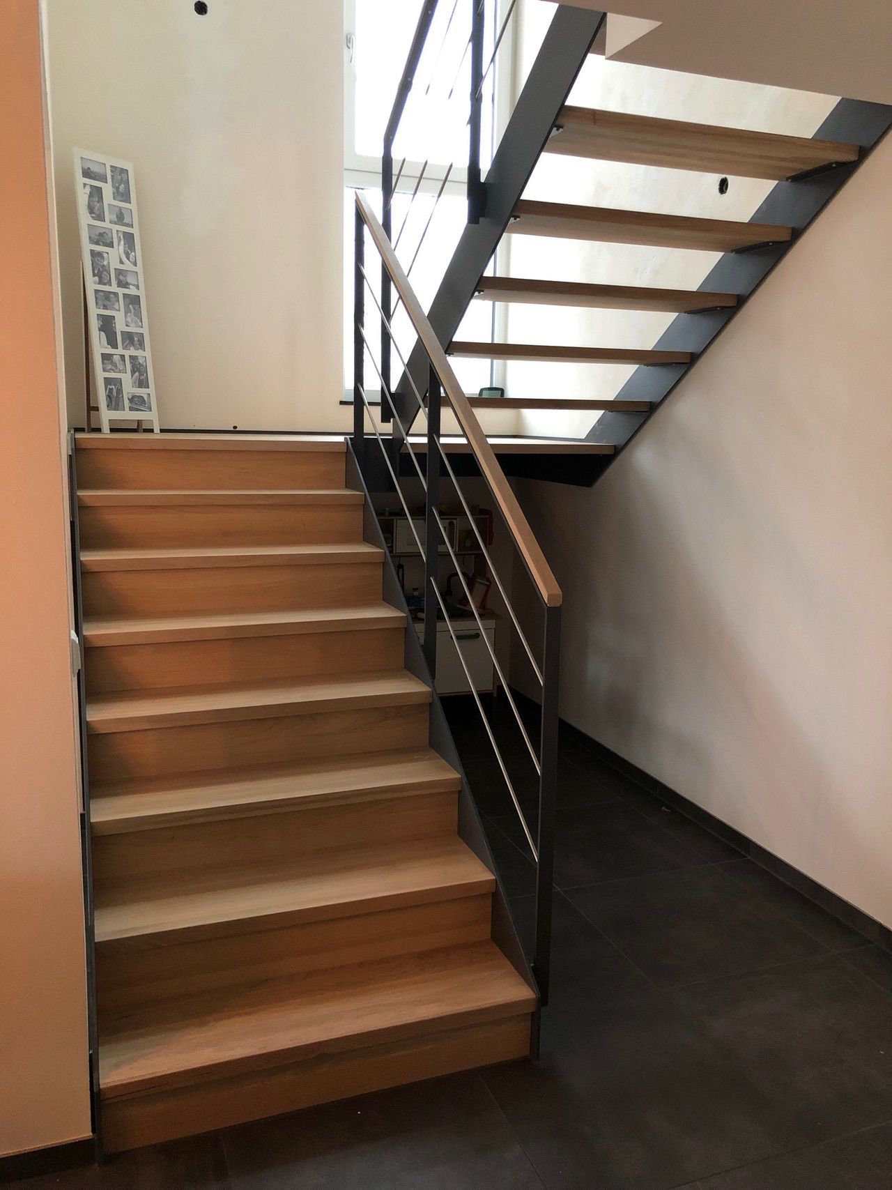 Eine Holztreppe mit einem Metallgeländer in einem Flur.