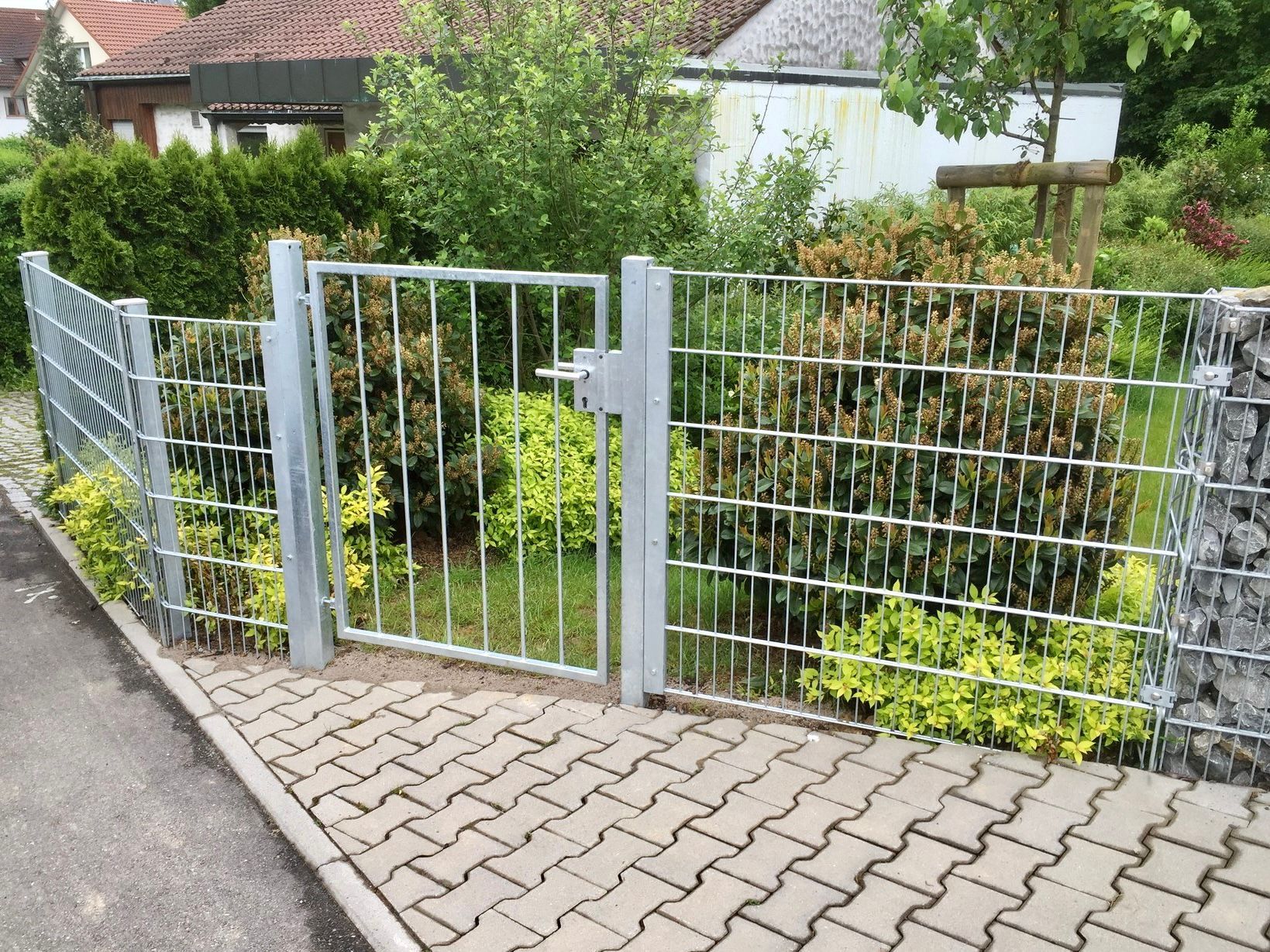 Ein Metallzaun mit einem Tor, das zu einem Garten führt