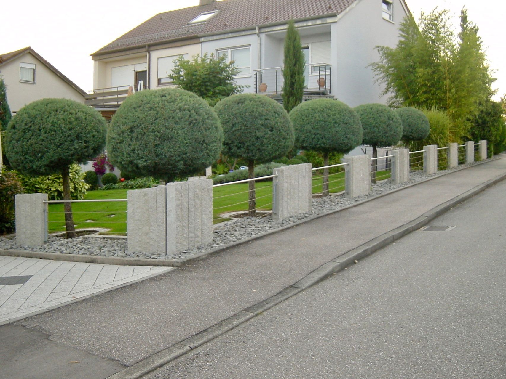 Ein Haus mit einem Zaun und Büschen davor