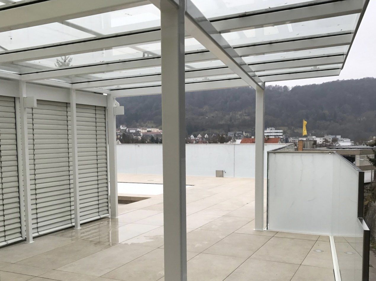 Ein Balkon mit Glasdach und Blick auf die Berge.