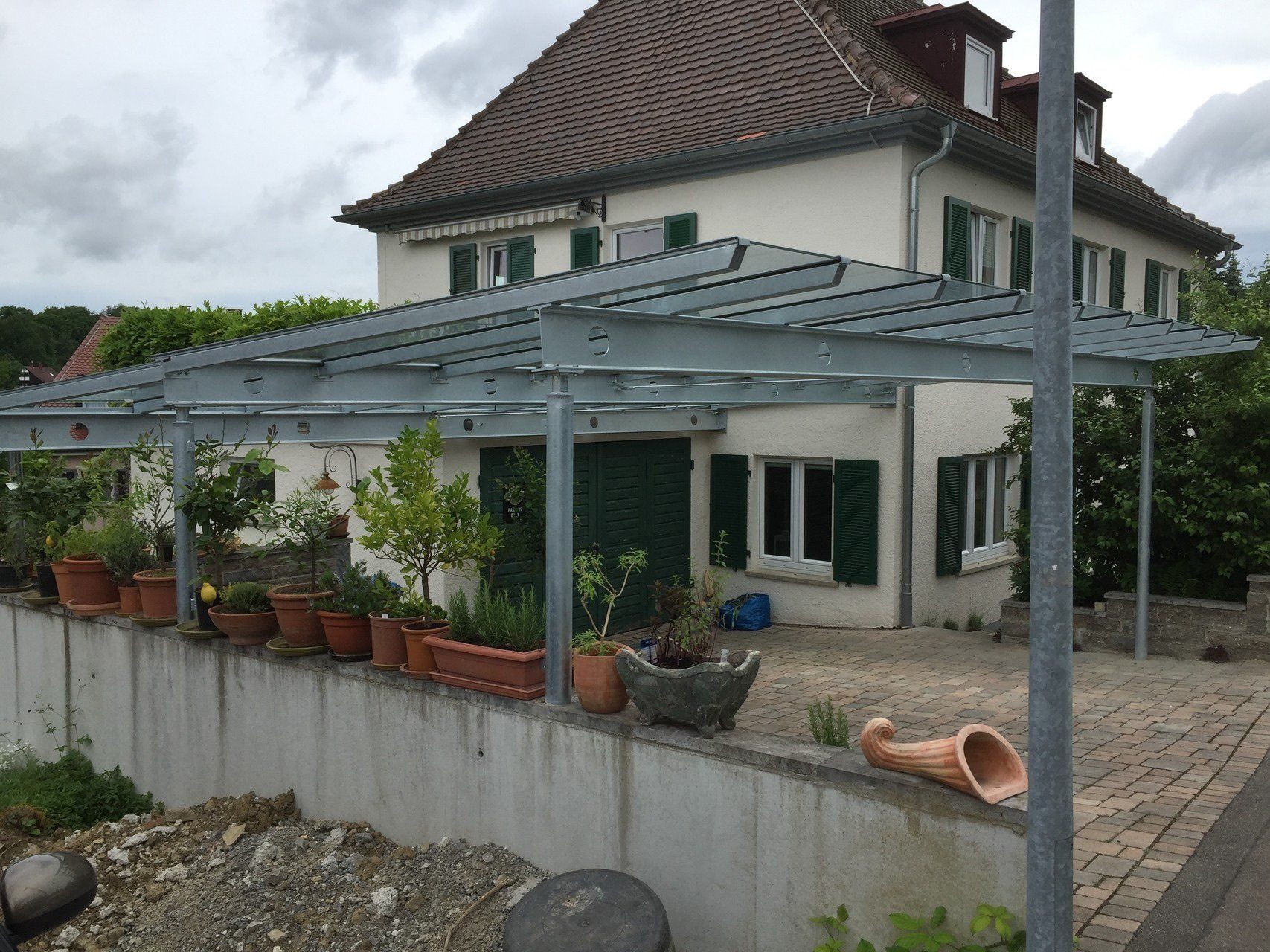 Ein Haus mit einer Pergola und Topfpflanzen davor