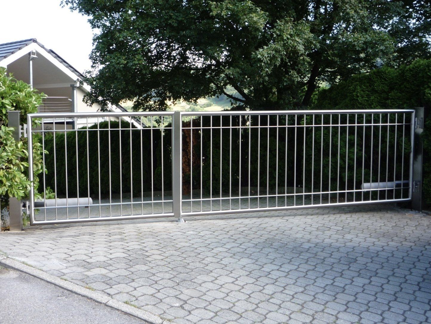 Ein Edelstahltor ist zu einer Einfahrt hin geöffnet