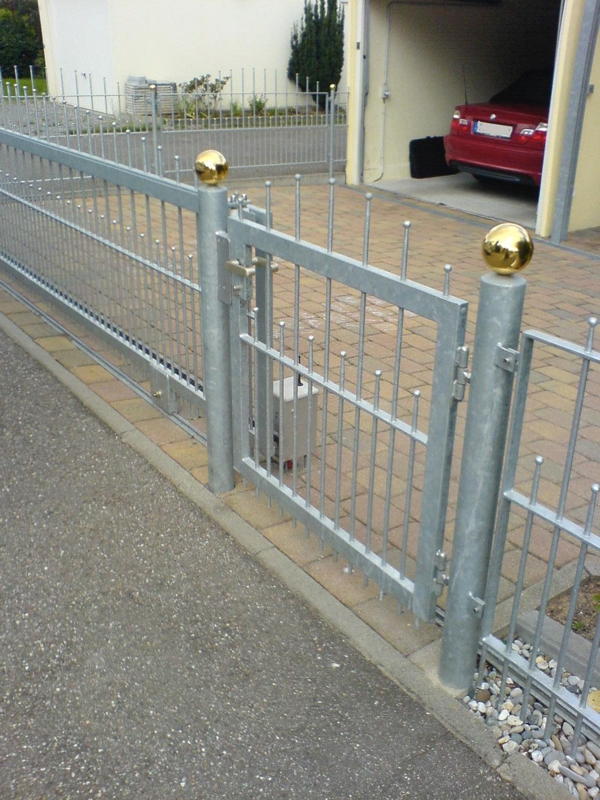 Ein Metallzaun mit einem dahinter geparkten roten Auto