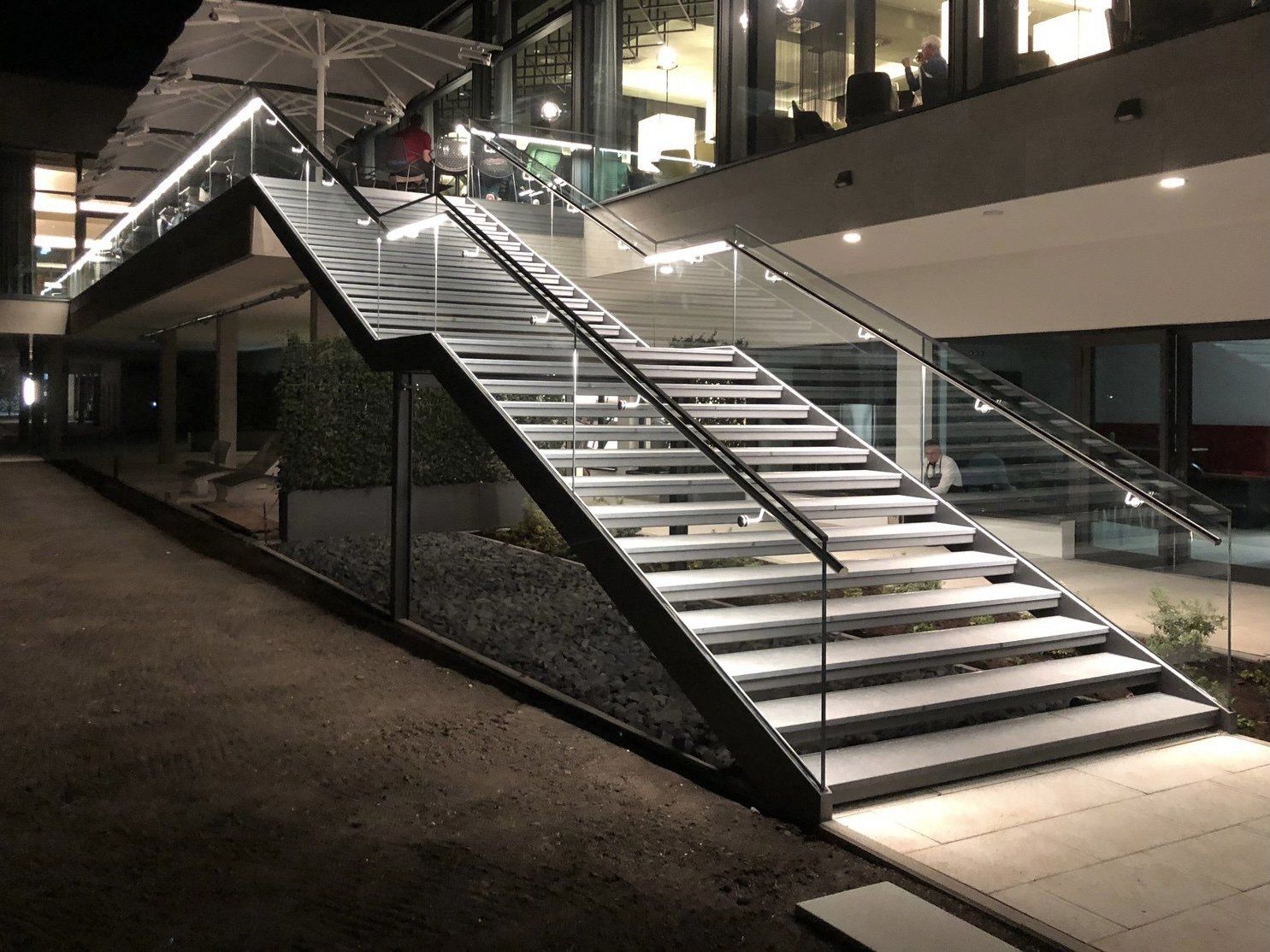 Eine Treppe mit Glasgeländer ist nachts beleuchtet.