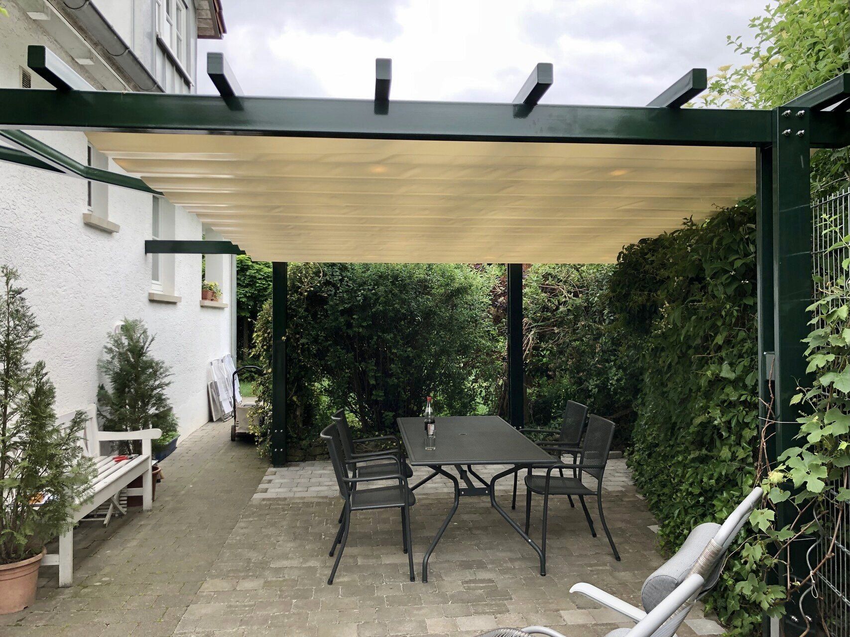 Eine Terrasse mit Tisch und Stühlen unter einer Pergola.