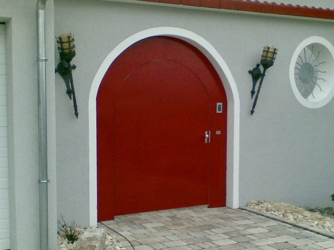 Eine rote Tür mit weißem Rand an einer grauen Wand