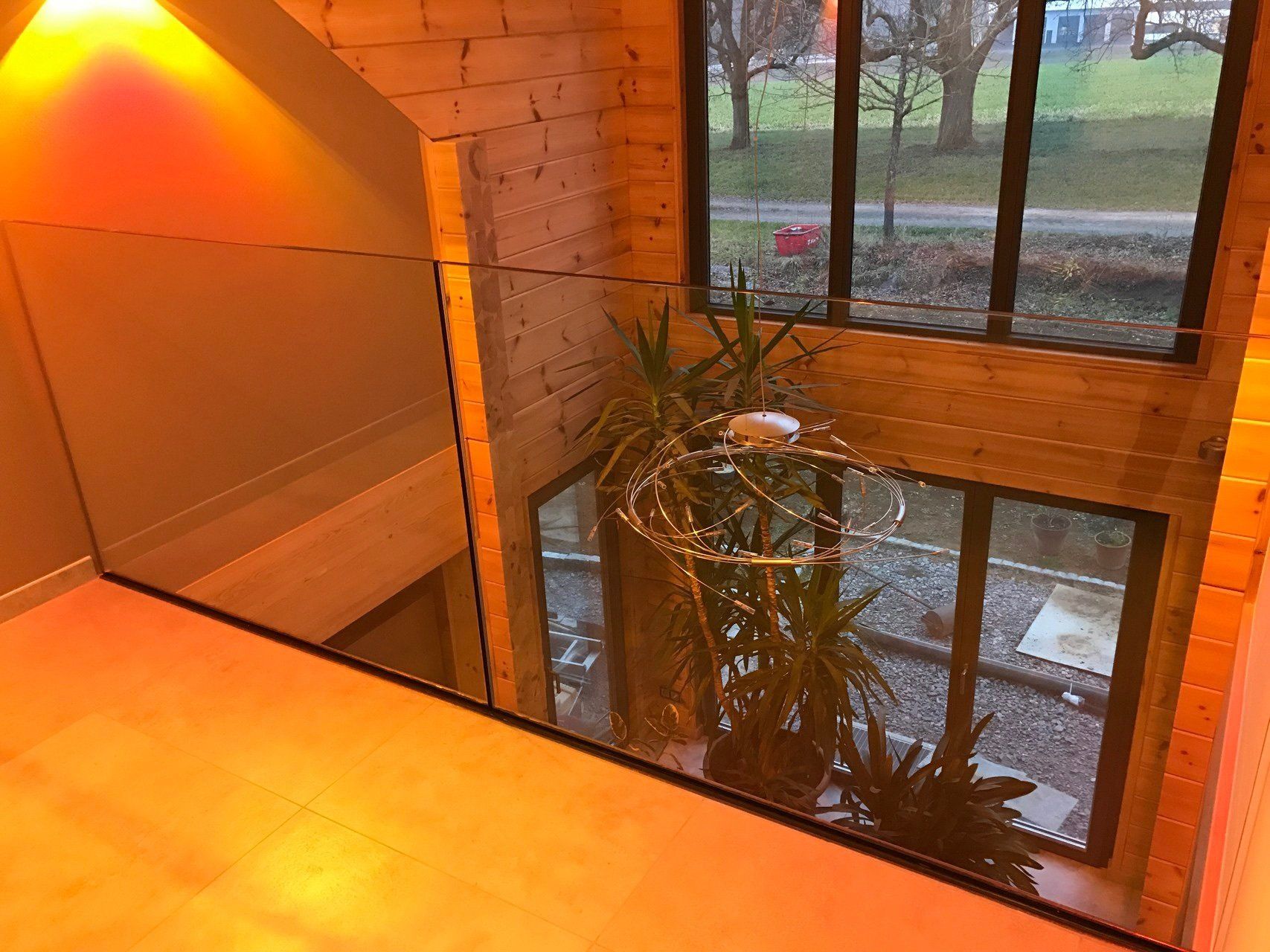 Eine Treppe mit einem Glasgeländer und einer Pflanze vor einem Fenster.