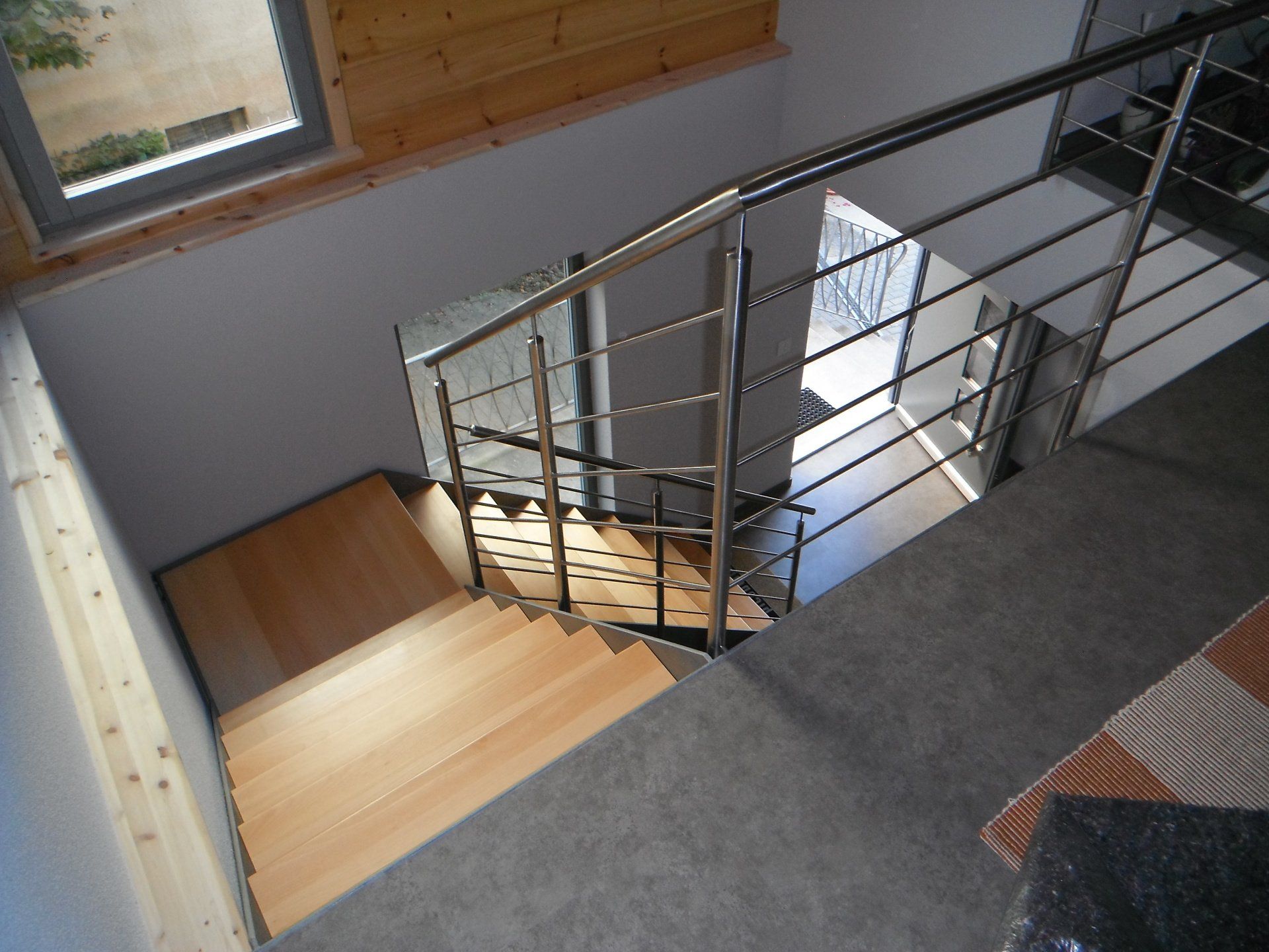 Eine Holztreppe mit einem Geländer aus Edelstahl