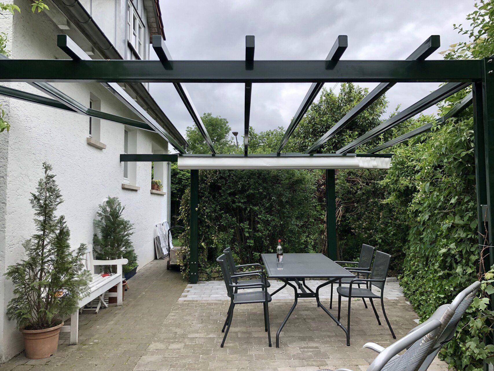 Eine Terrasse mit Tisch und Stühlen unter einer Pergola.