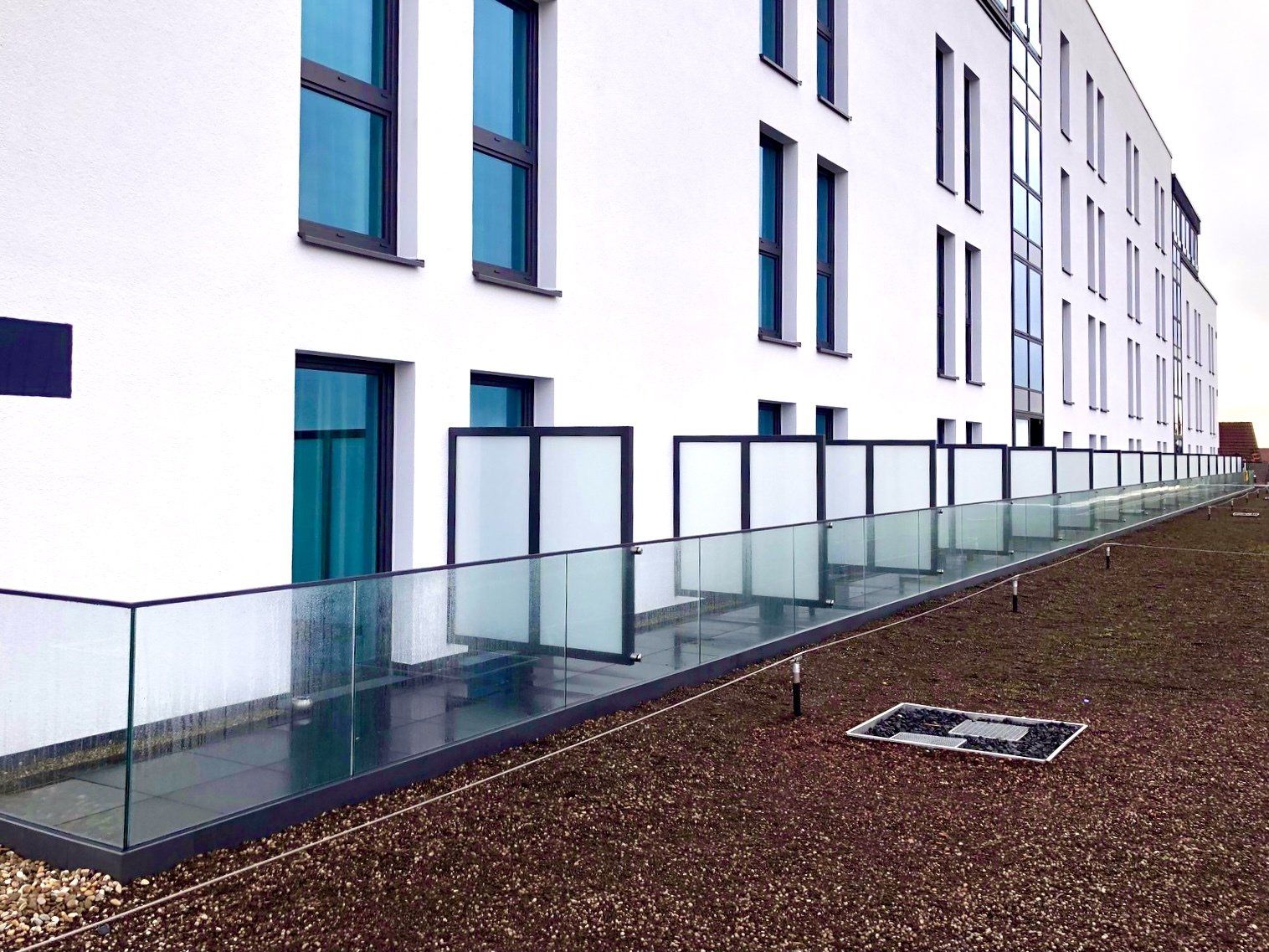 Ein weißes Gebäude mit einem Glasgeländer an der Seite.