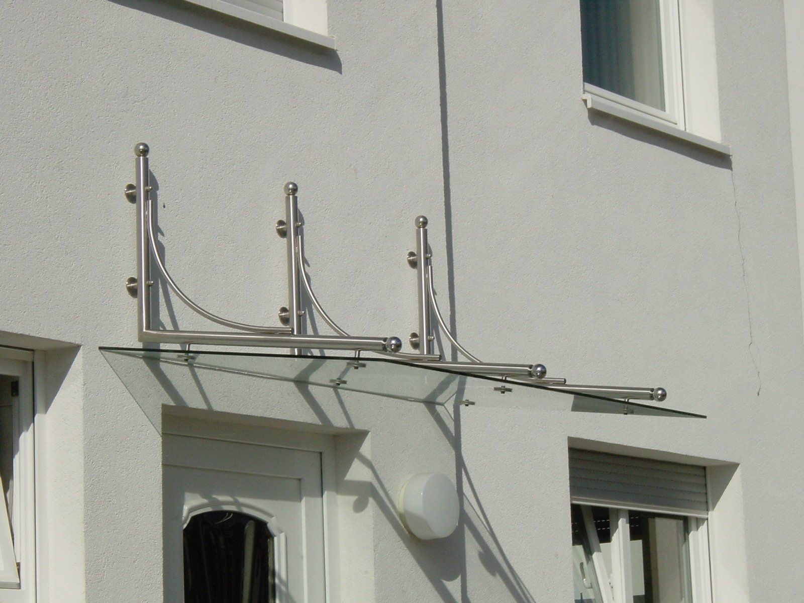 Ein weißes Gebäude mit einem Glasdach über der Tür