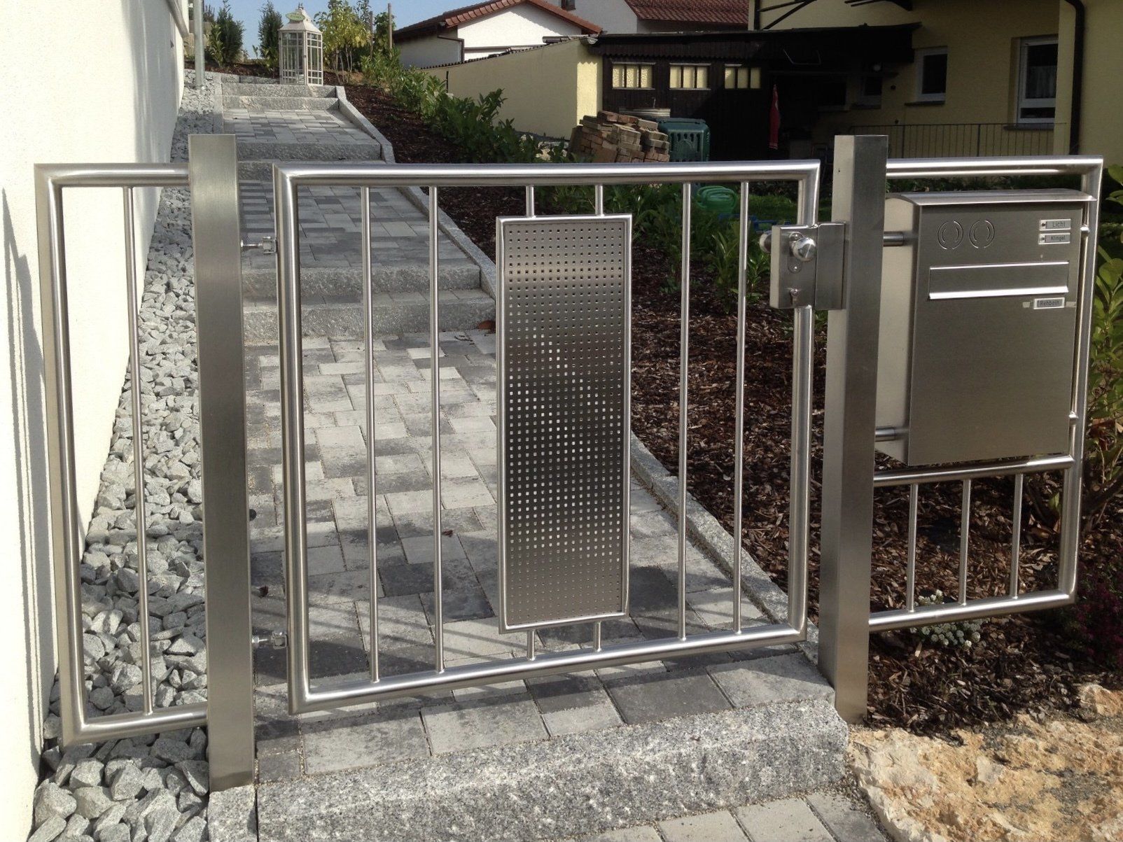 Ein Edelstahltor mit einem Briefkasten daneben
