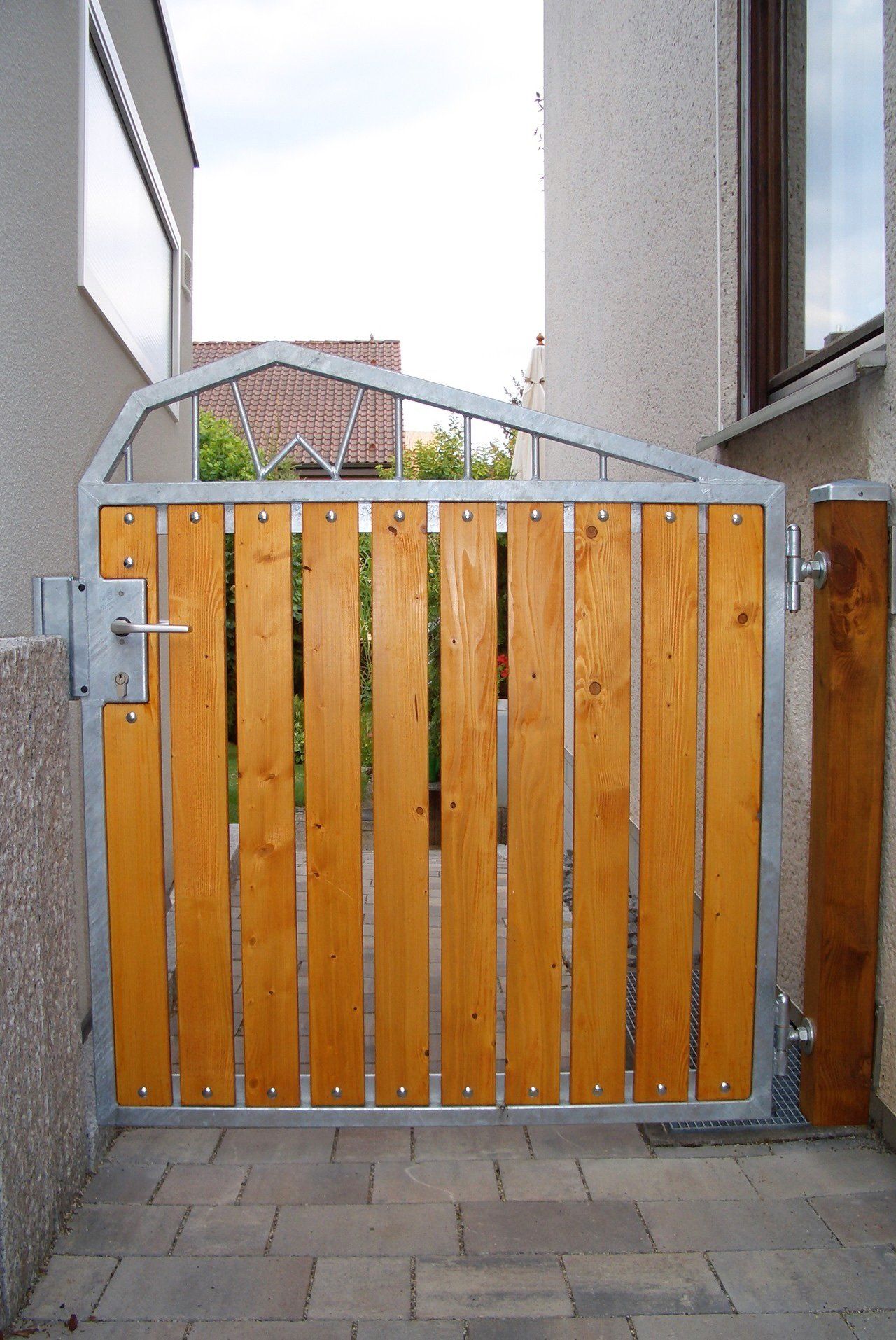 Ein Holztor mit einem Metallrahmen befindet sich vor einem Gebäude