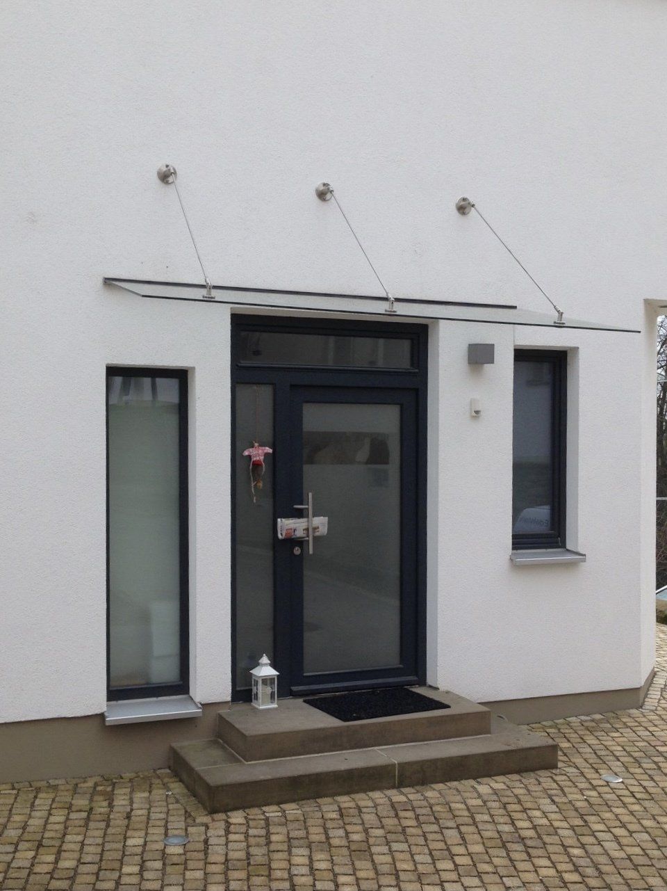 Ein weißes Gebäude mit einer schwarzen Tür und schwarzen Fenstern