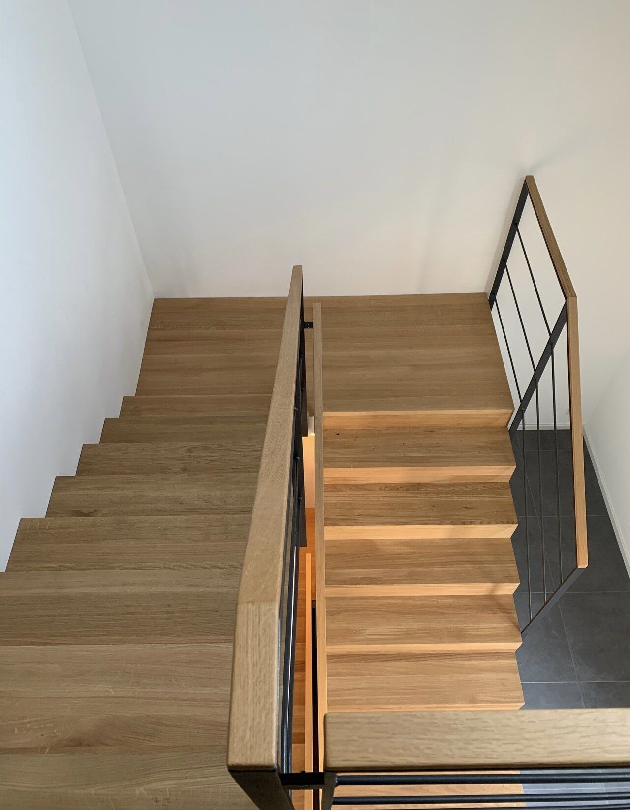 Eine Holztreppe mit einem Metallgeländer und einer weißen Wand