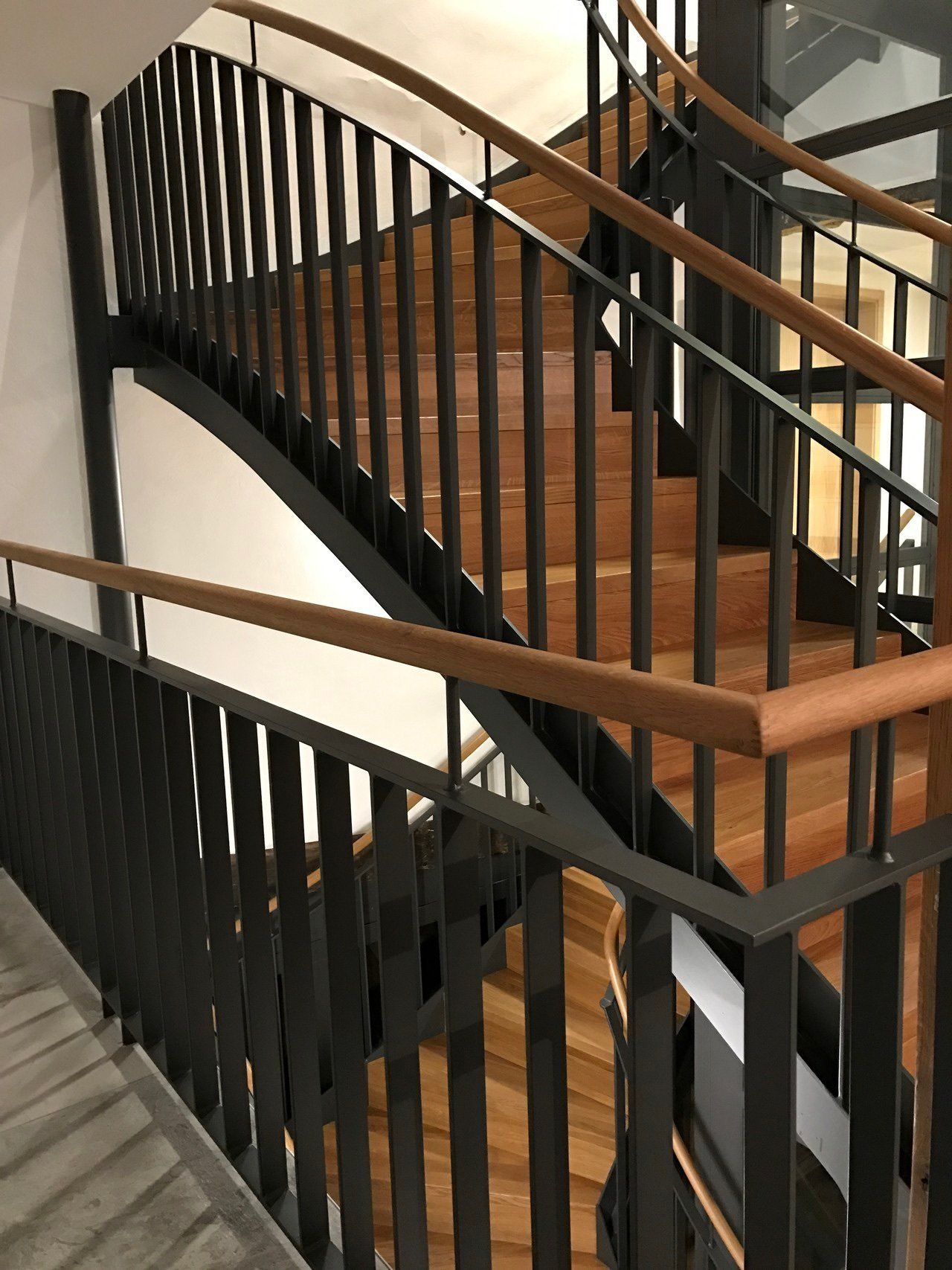 Eine Wendeltreppe mit schwarzem Geländer und Holzhandläufen